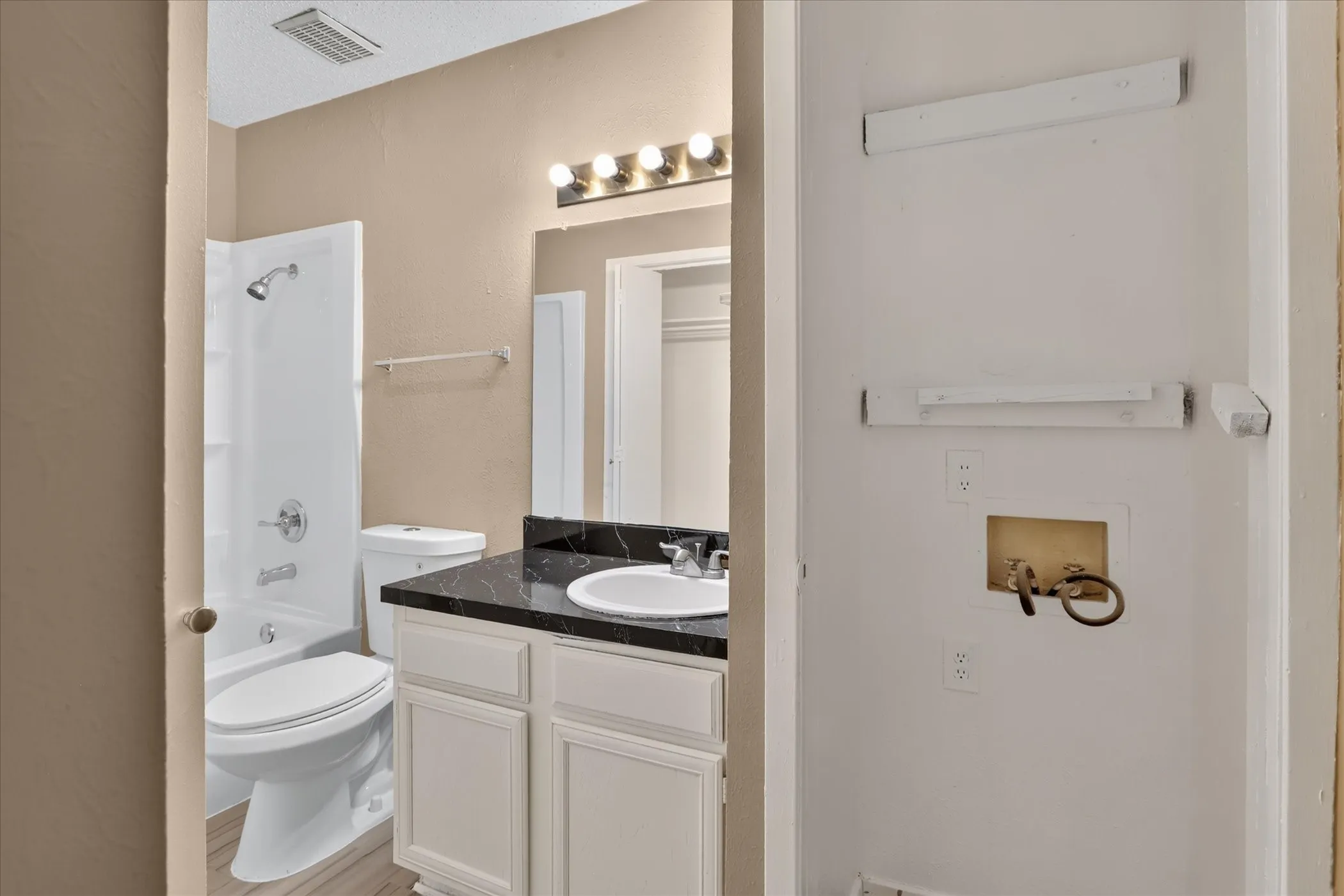 Bathroom with a white vanity, dark countertop, and integrated sink