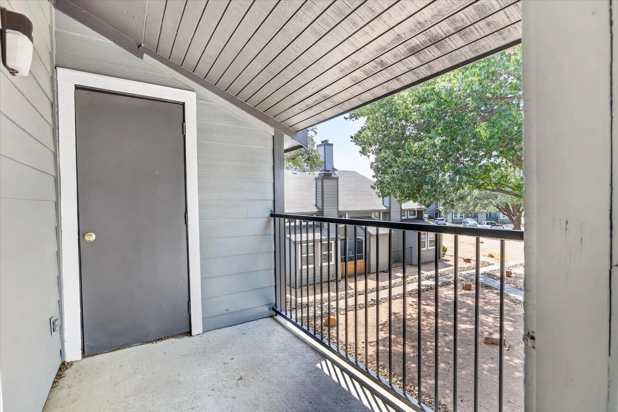 Covered outdoor balcony with concrete flooring, accented by a black metal railing