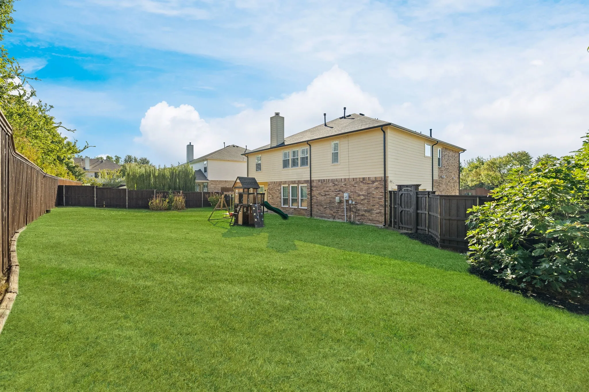 Expansive green lawn with a wooden fence boundary