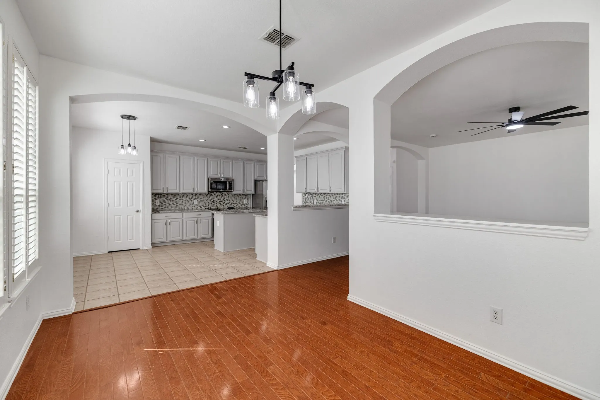 Hardwood flooring, arched doorways, window shutters, recessed lighting, and a modern ceiling fan