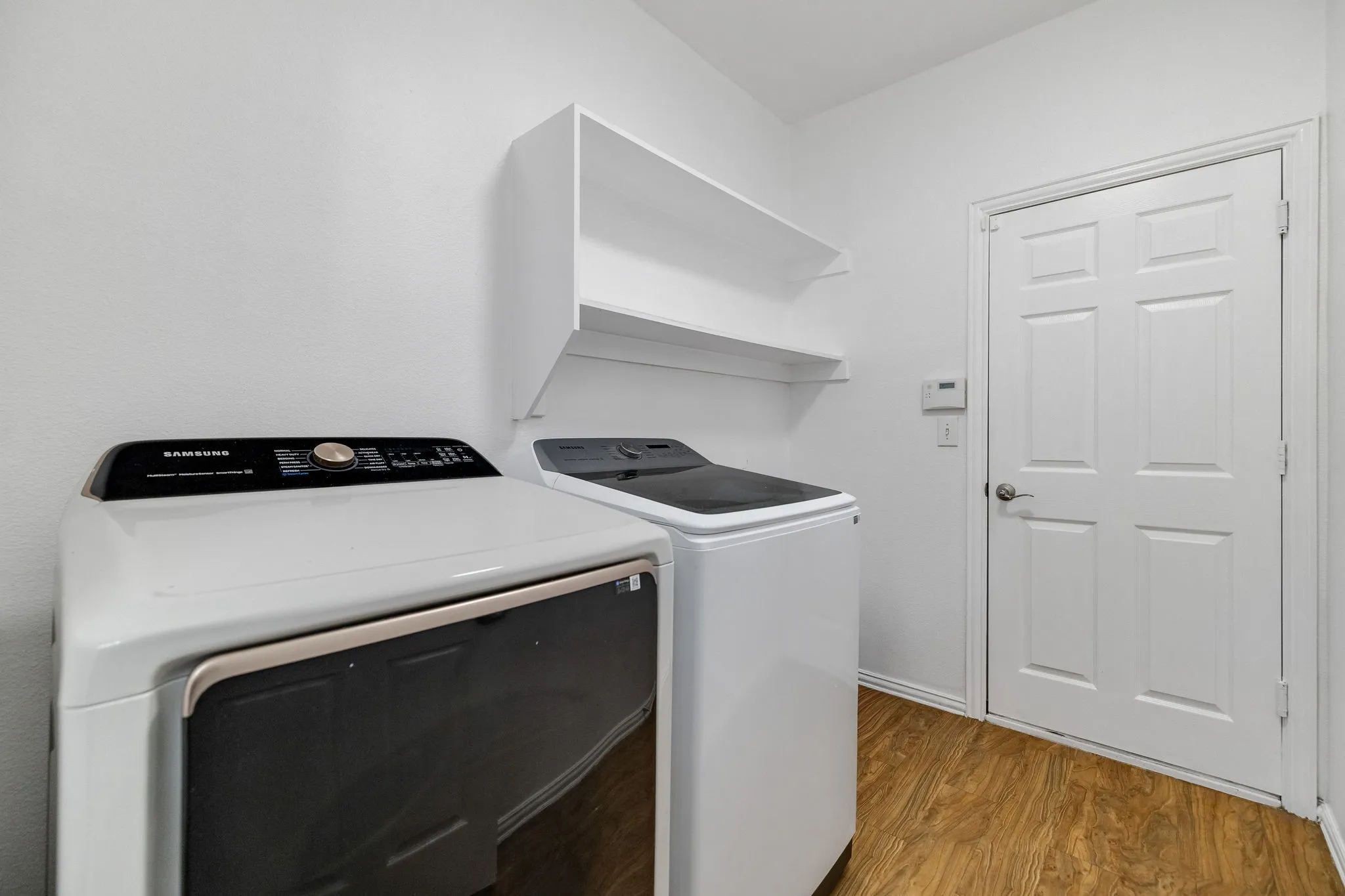 Wall-mounted shelving, wood-finish flooring, and a paneled door