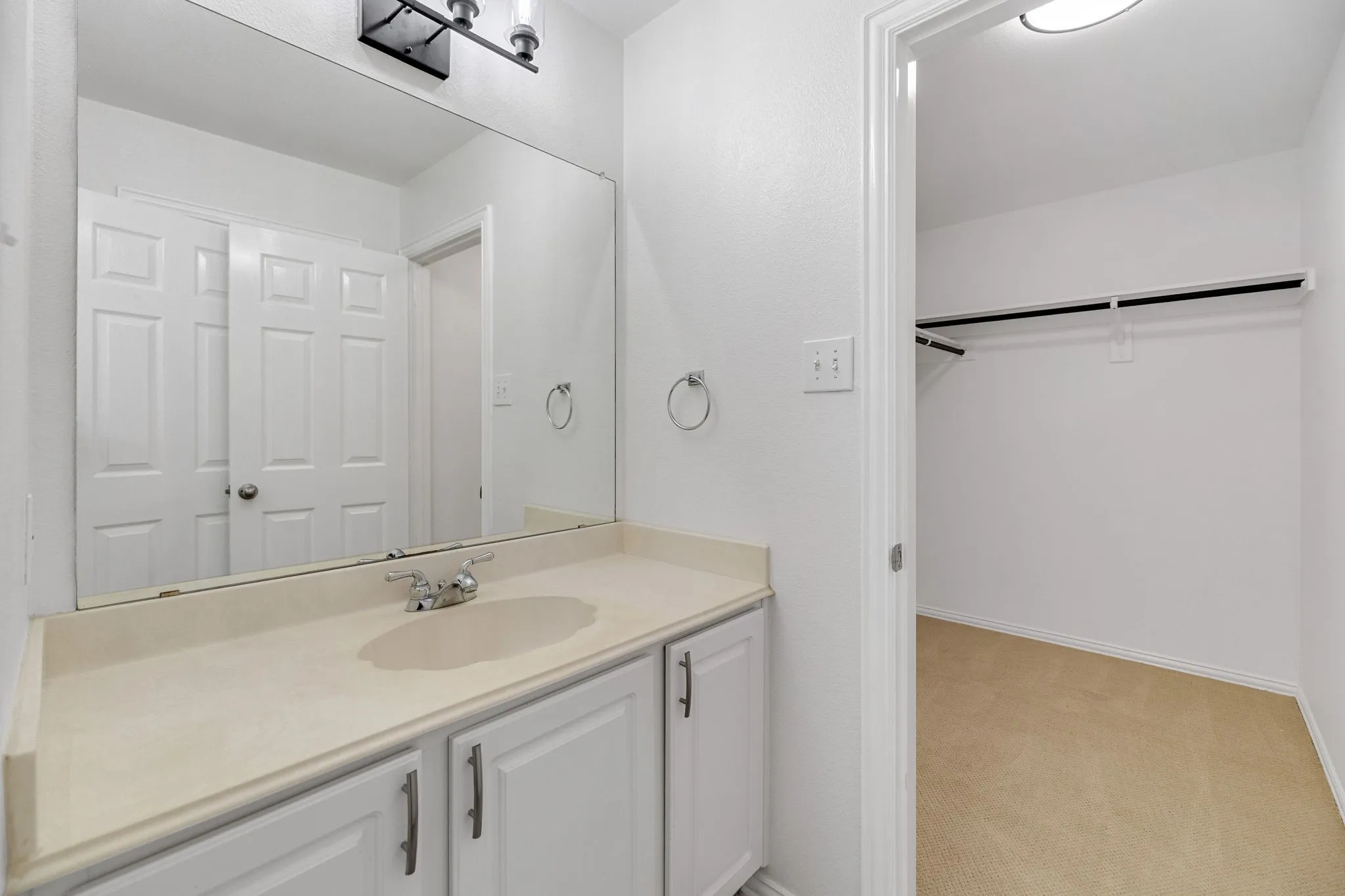 Vanity with integrated sink, chrome faucet, and white cabinetry