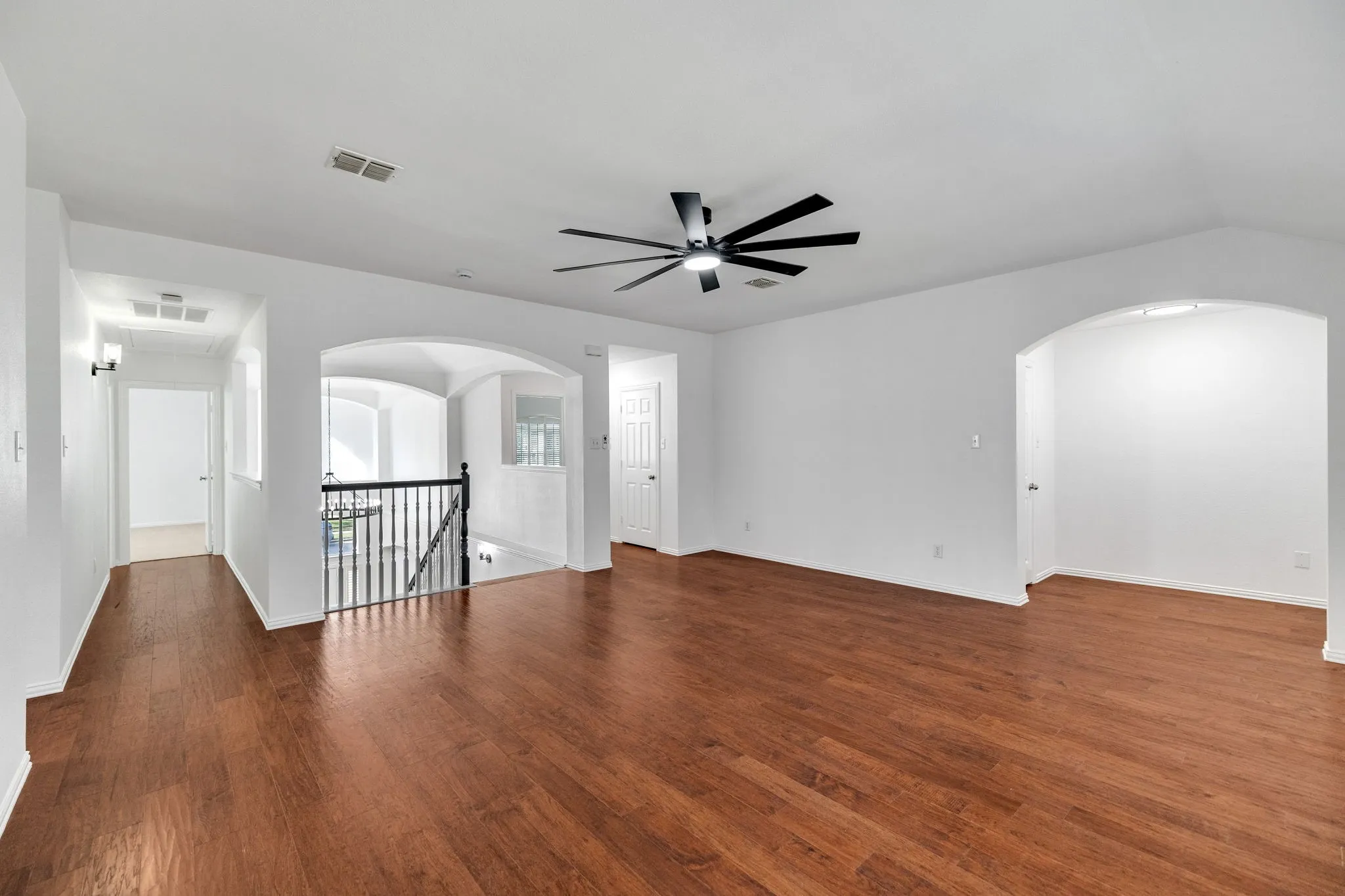 Hardwood-finish flooring, recessed lighting, contemporary ceiling fan, arched doorways, and wrought iron balusters