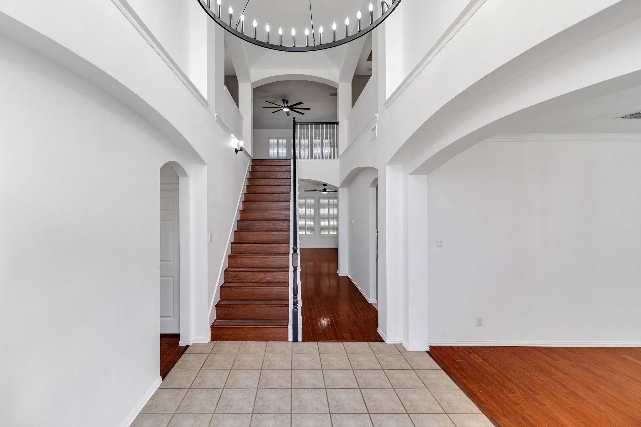 Two-story entryway with a decorative chandelier, a wood staircase, and an arched entry
