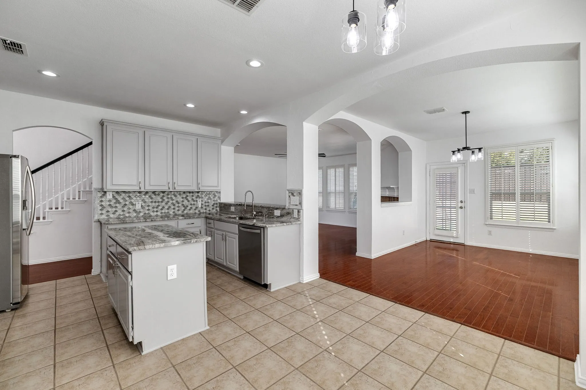 Kitchen featuring light gray cabinetry, stainless steel appliances, a mosaic tile backsplash, and a central island with a stone countertop