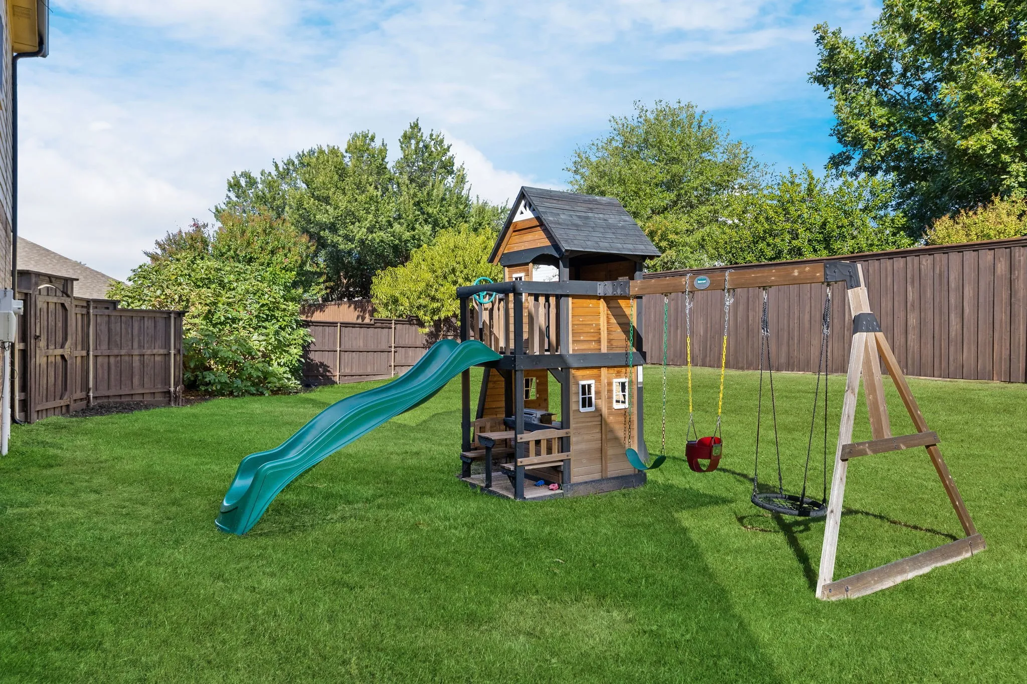 Expansive grassy lawn with a wood privacy fence and mature trees