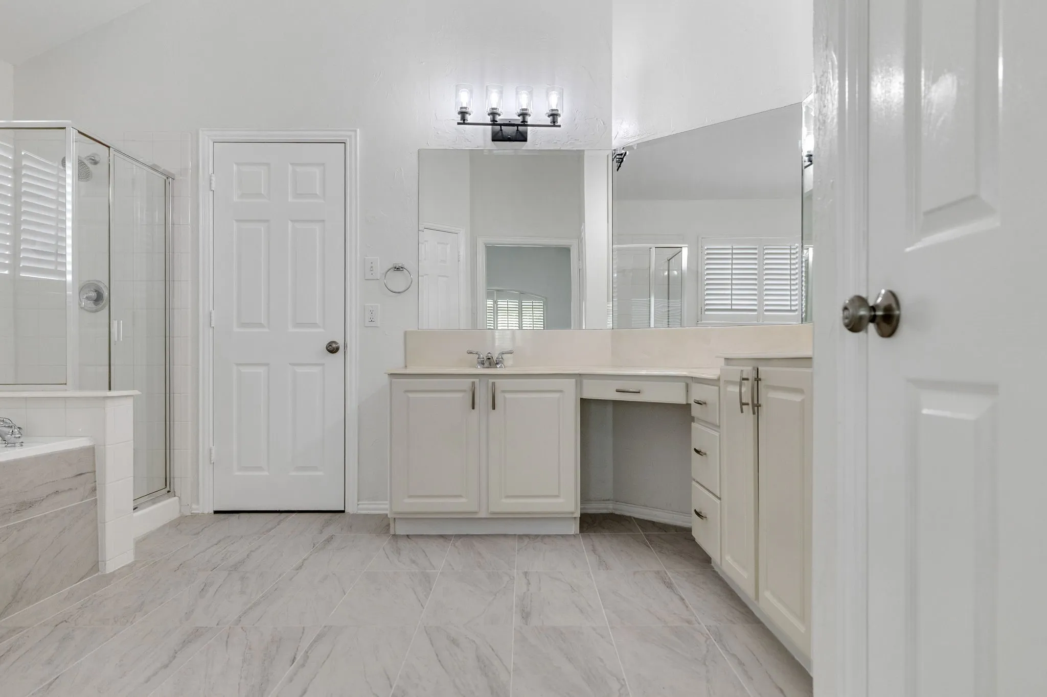 Dual vanity with integrated sink, glass-enclosed shower, built-in bathtub with tiled surround, wood-finish flooring, and vanity lighting