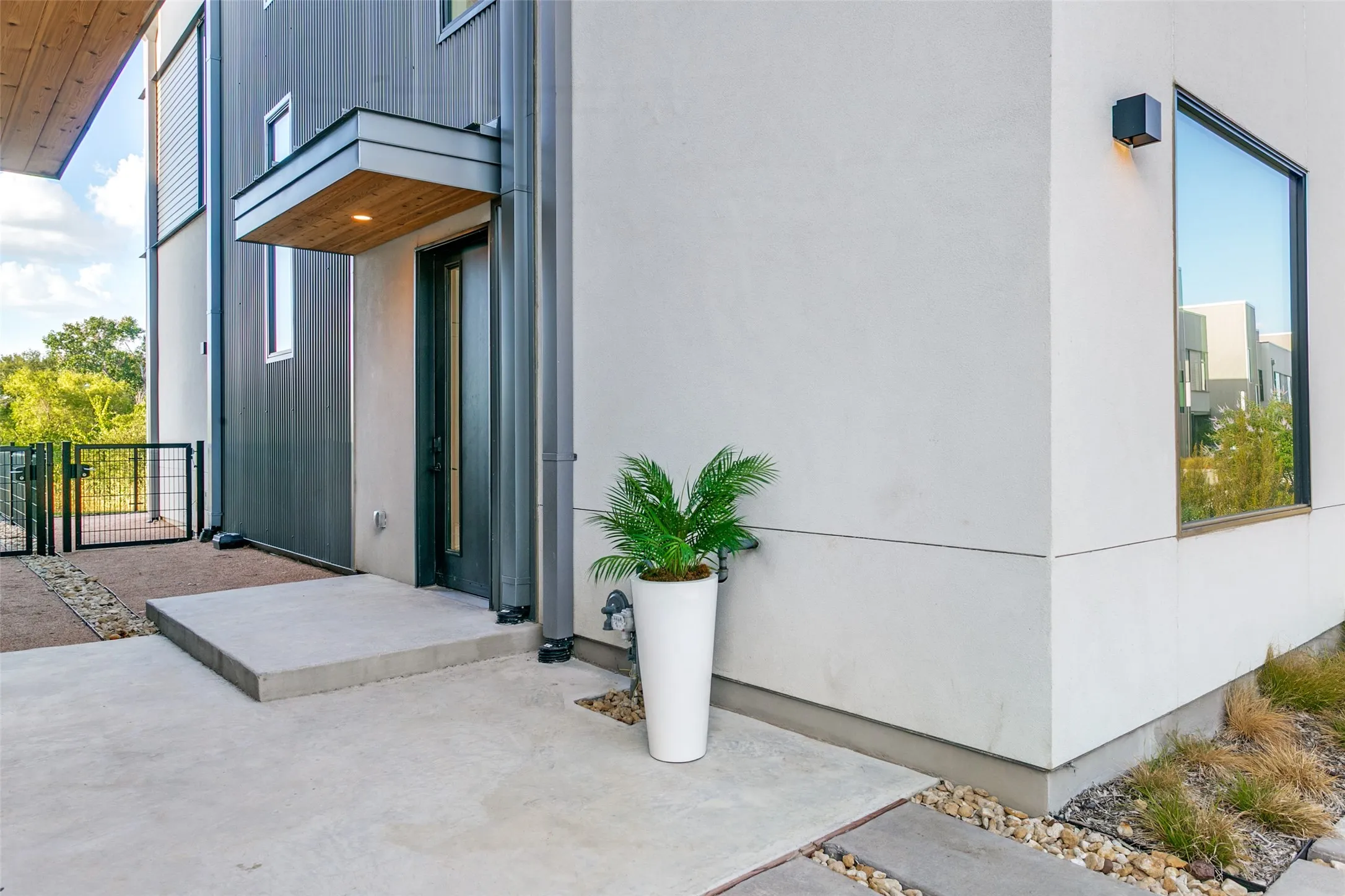 Modern exterior featuring entry with wood-finish soffit, and a peek at your back view.  Let the HOA take care of front landscaping, and use your imagination for your back gated courtyard.