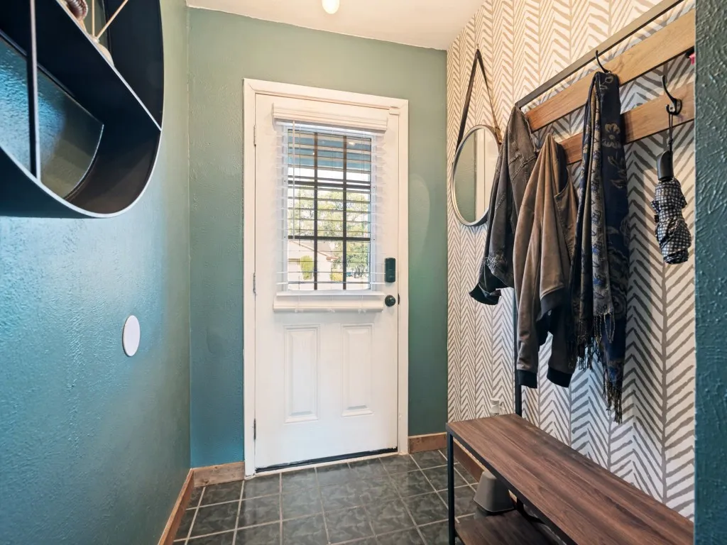 Entryway featuring a paneled door with window, tile flooring, and a patterned accent wall
