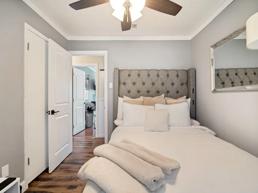 Wood-finish flooring, crown molding, and a ceiling fan with integrated lighting
