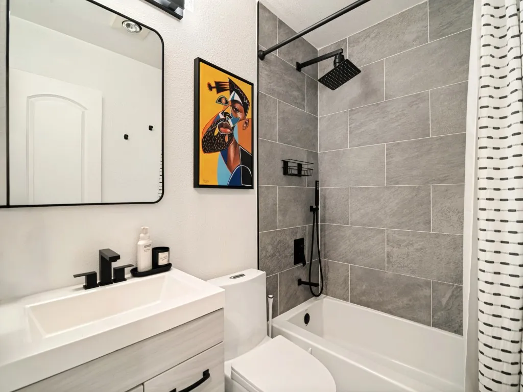 Bathroom featuring a white vanity with integrated sink, matte black faucet, and a rectangular mirror