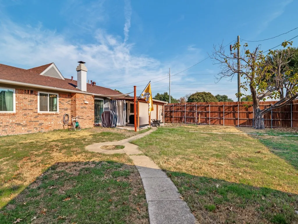 Expansive backyard featuring a privacy fence, concrete pathway, and a patio area