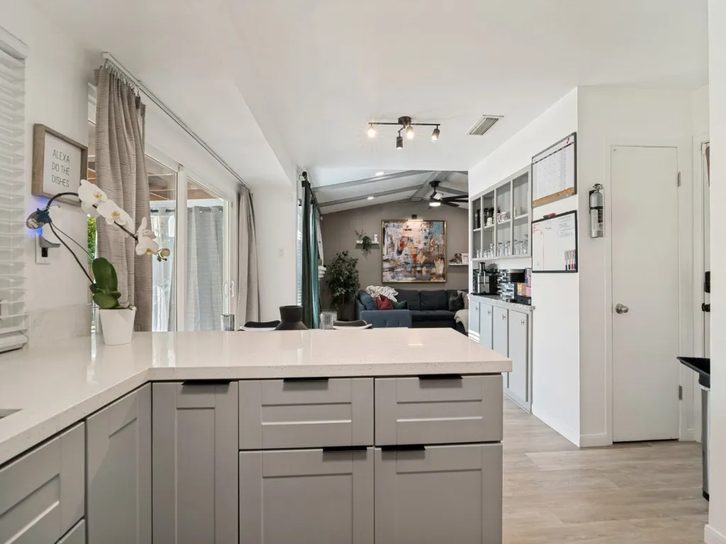 Kitchen featuring light gray cabinetry with dark hardware, solid surface countertops, and wood-finish flooring