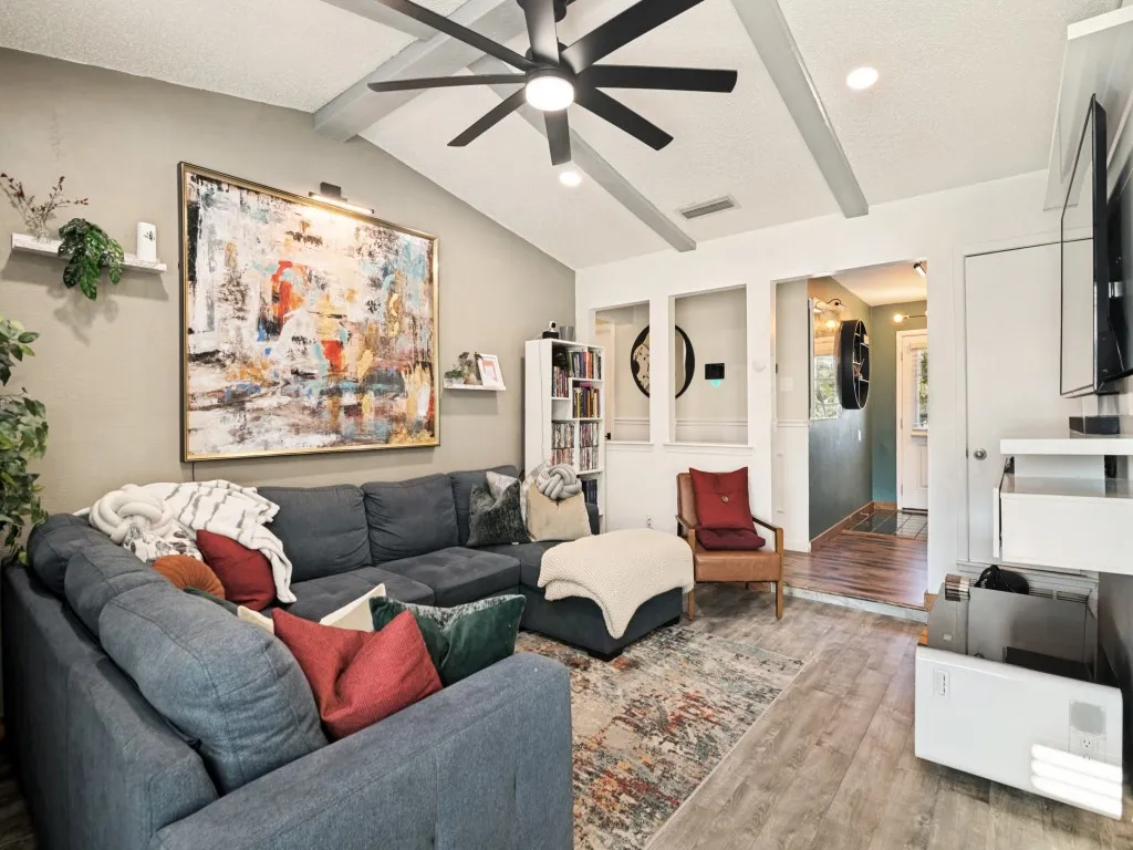 Vaulted ceiling with exposed beams, wood-finish flooring, recessed lighting, ceiling fan, and built-in shelving