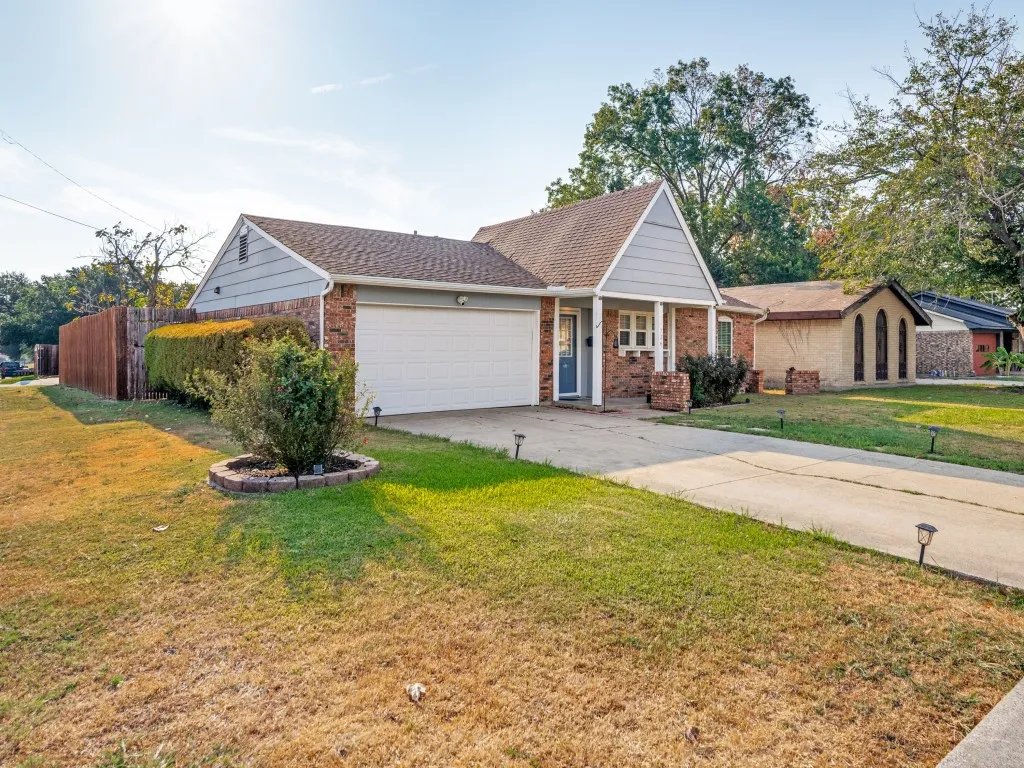 Brick and siding exterior with an attached garage, covered front porch, concrete driveway, and a wood privacy fence