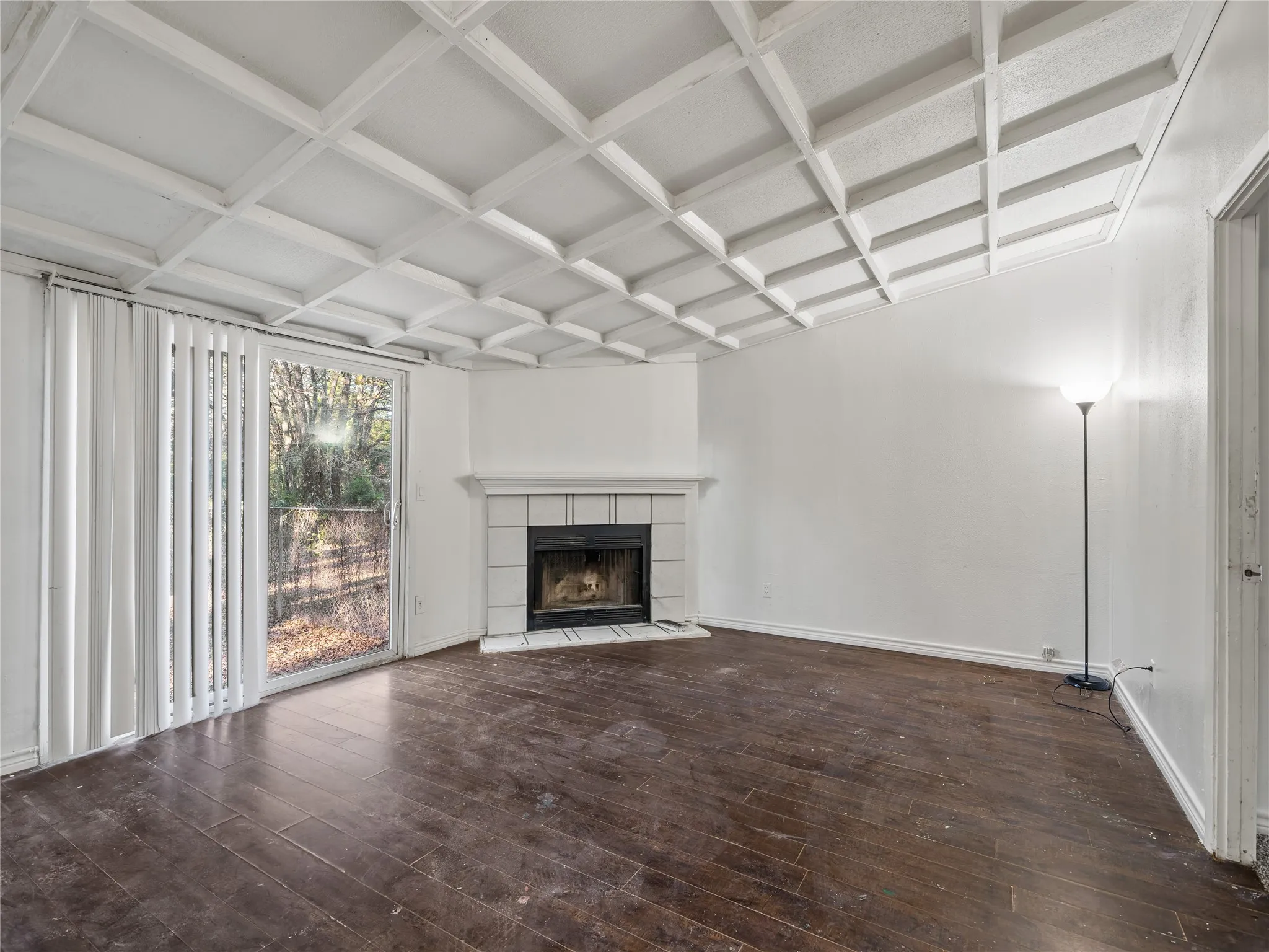 Living area featuring a coffered ceiling, wood-finish flooring, a fireplace with a tile surround, and a sliding glass door