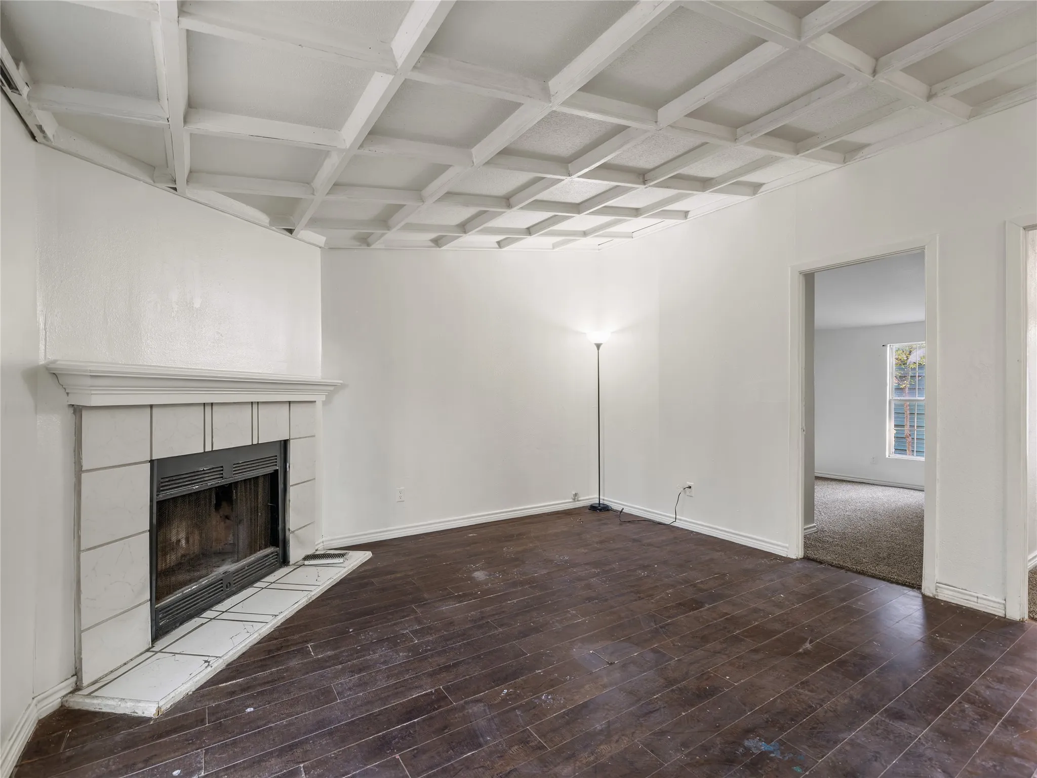 Coffered ceiling with a white finish, tile-surround fireplace with a mantel, and dark wood-finish flooring