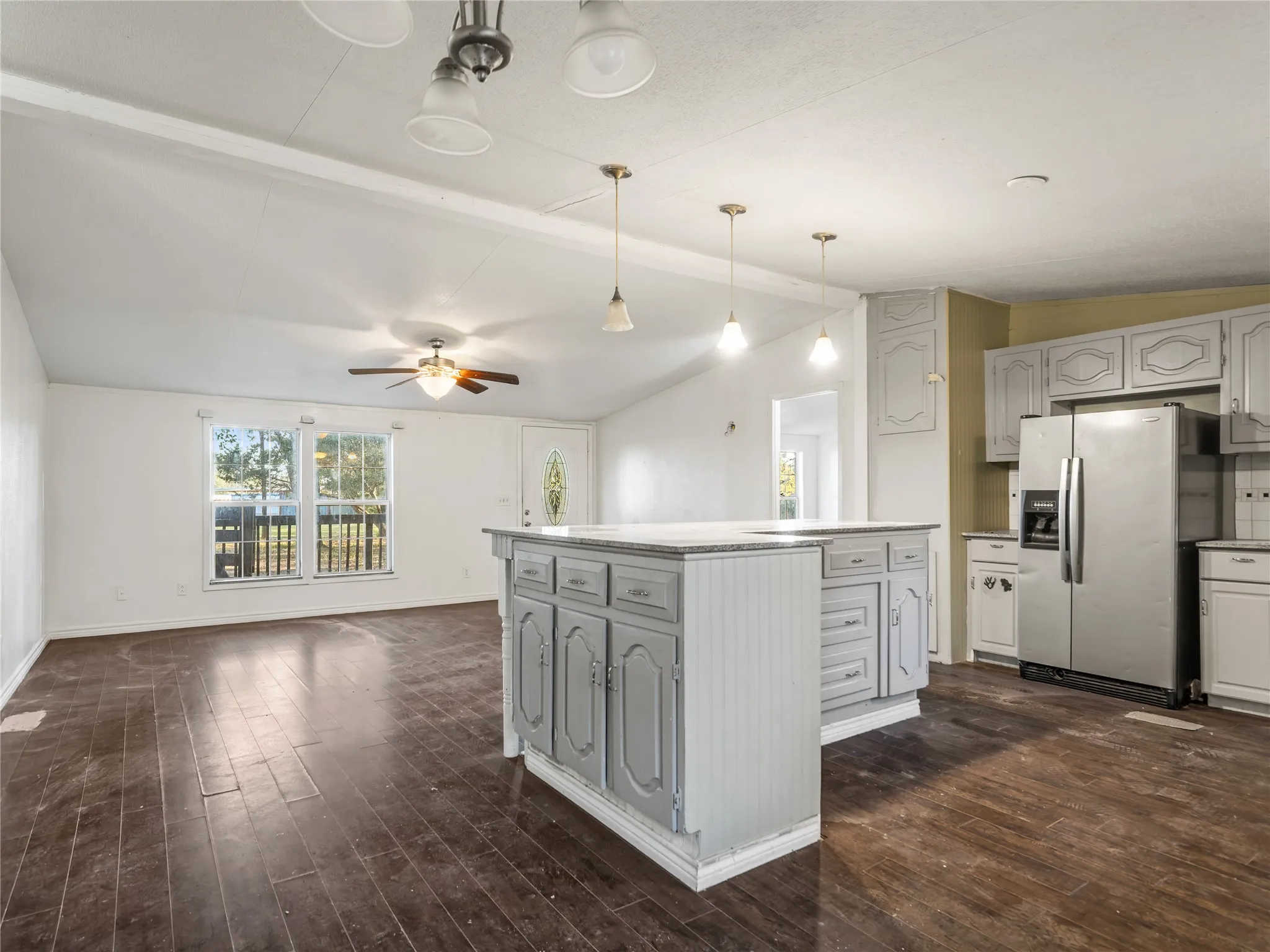 Open-concept living area featuring a vaulted ceiling and wood-finish flooring