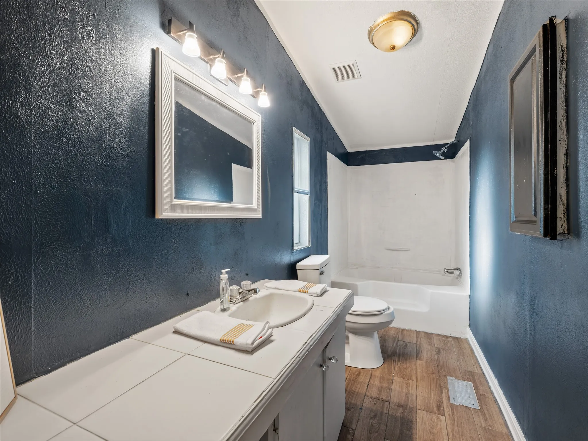 Wood-finish flooring with a white vanity featuring a single basin sink