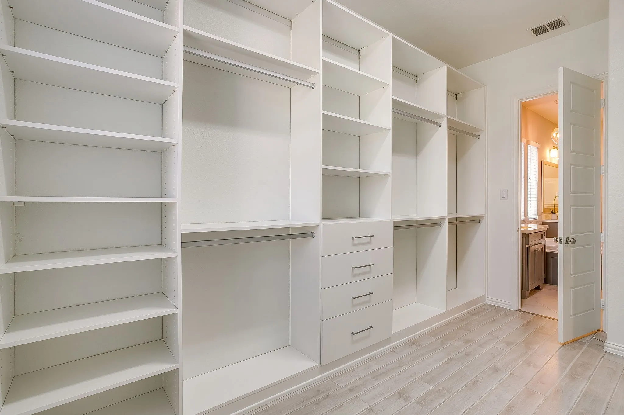 Custom Primary Closet opens into large laundry room with storage