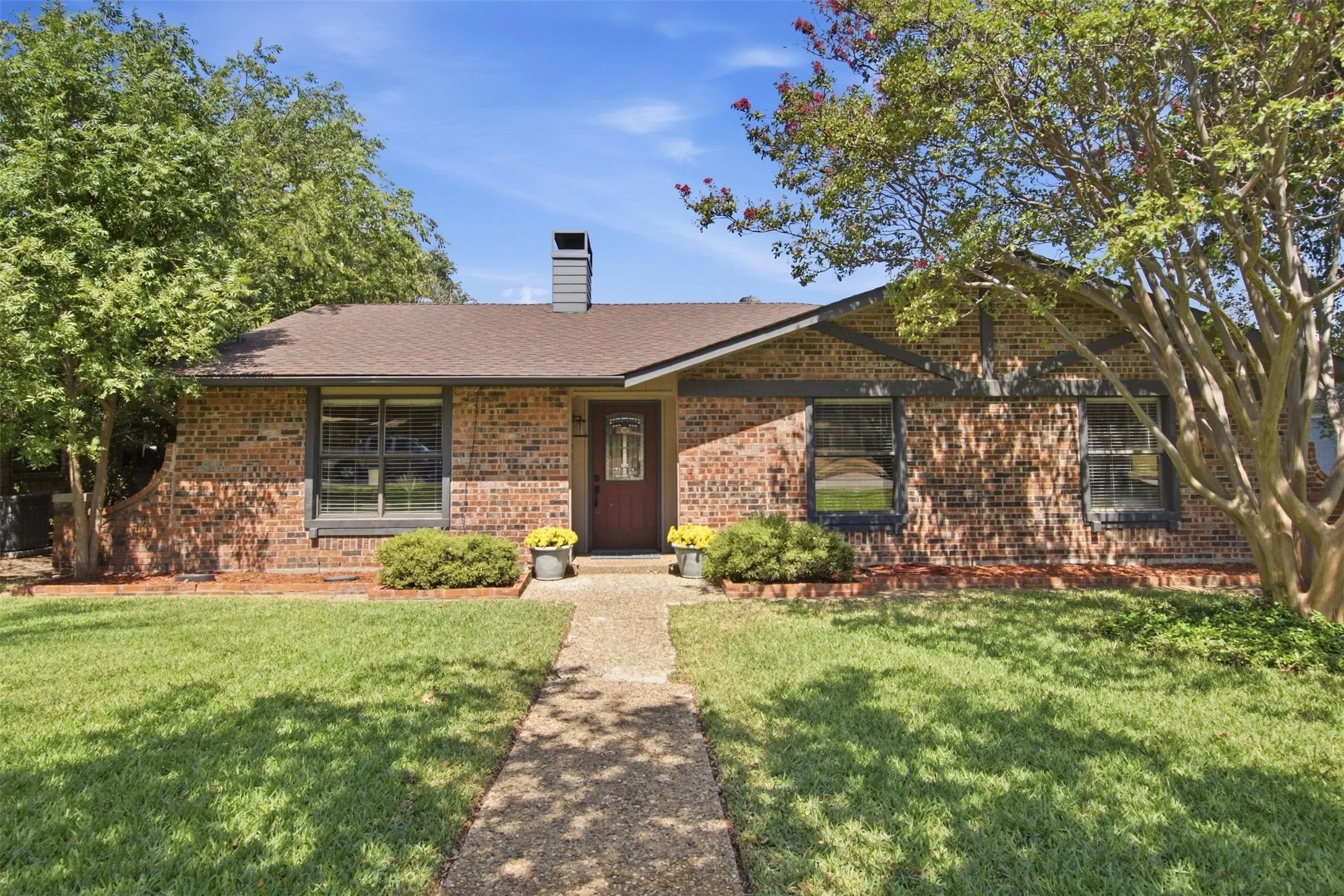 Brick exterior with dark trim accents, covered entry, and a prominent chimney