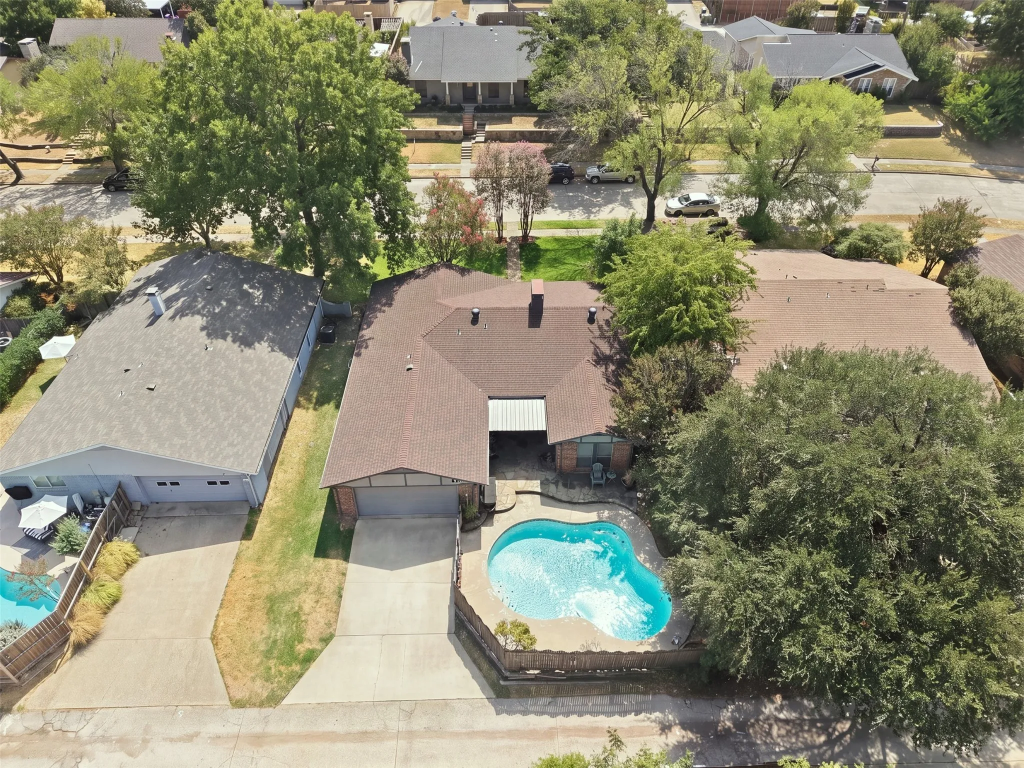 Exterior featuring a private pool, an attached garage, a detached garage, and mature trees