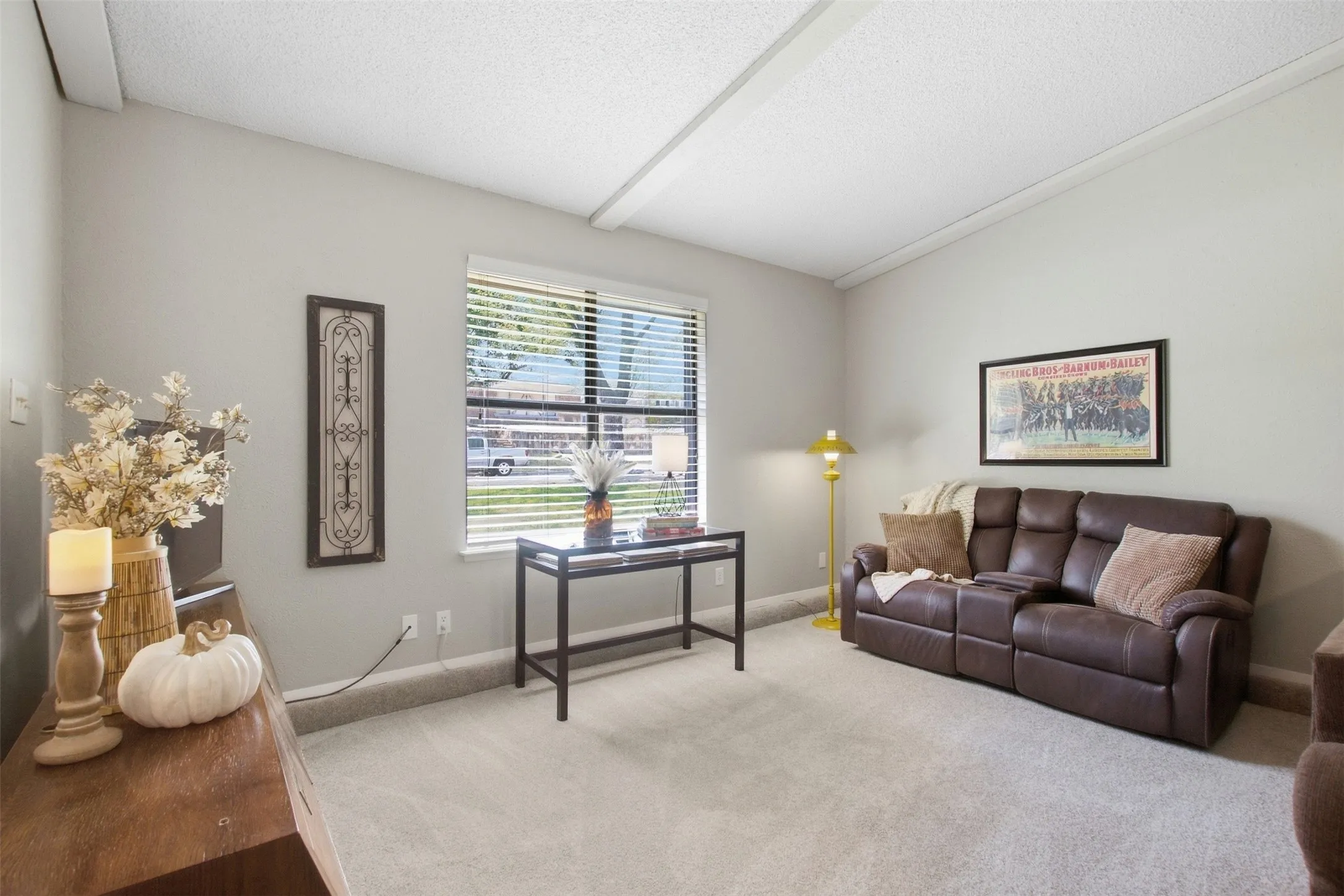 Vaulted ceiling with exposed beams, window with blinds, and neutral wall color