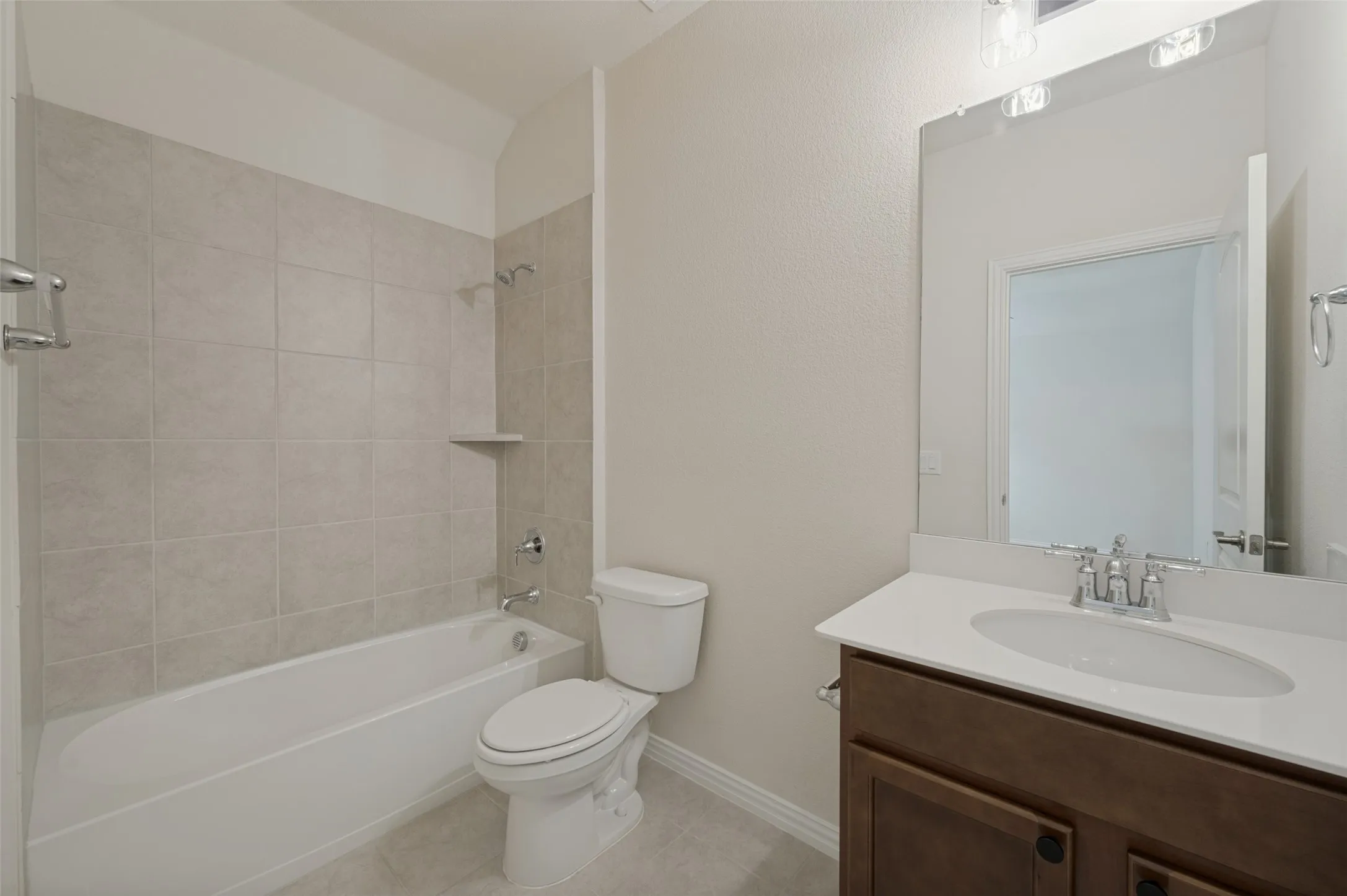 Tub-shower combination with light-toned wall tile and integrated shelf
