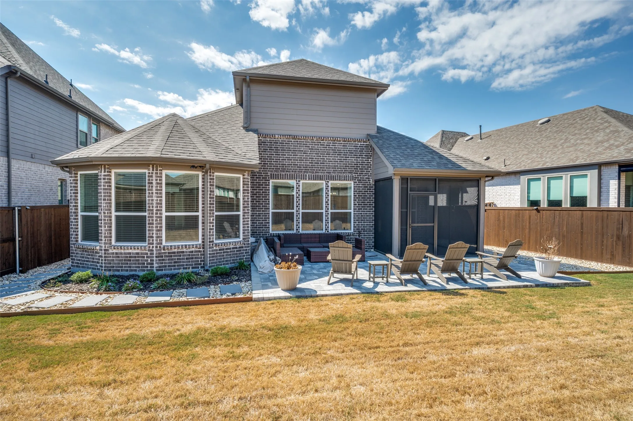 Brick exterior with an octagonal bay window, a screened patio, and a stone paver patio