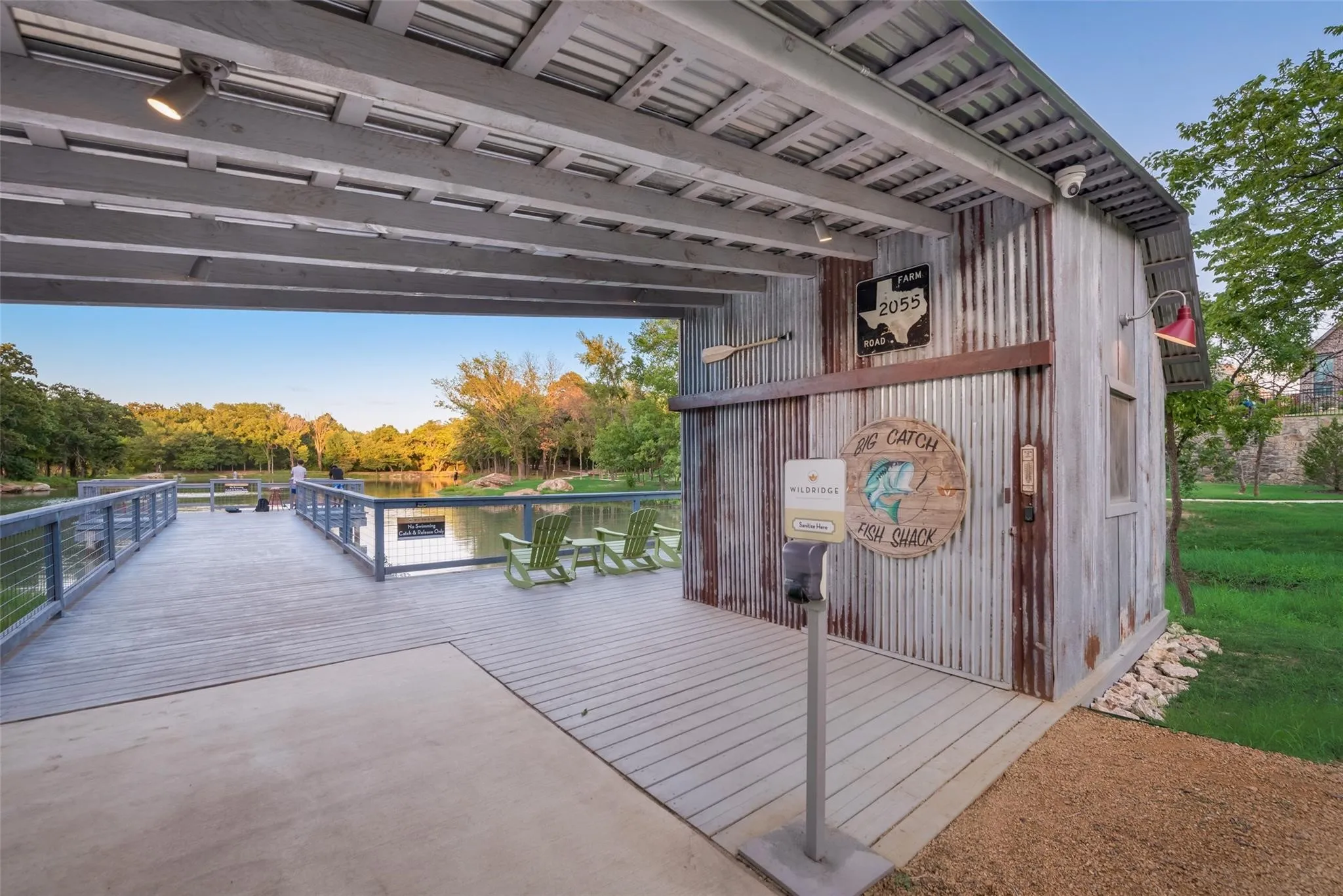 Covered outdoor structure with corrugated metal siding, an extended pier over water, and a slatted wood-finish deck