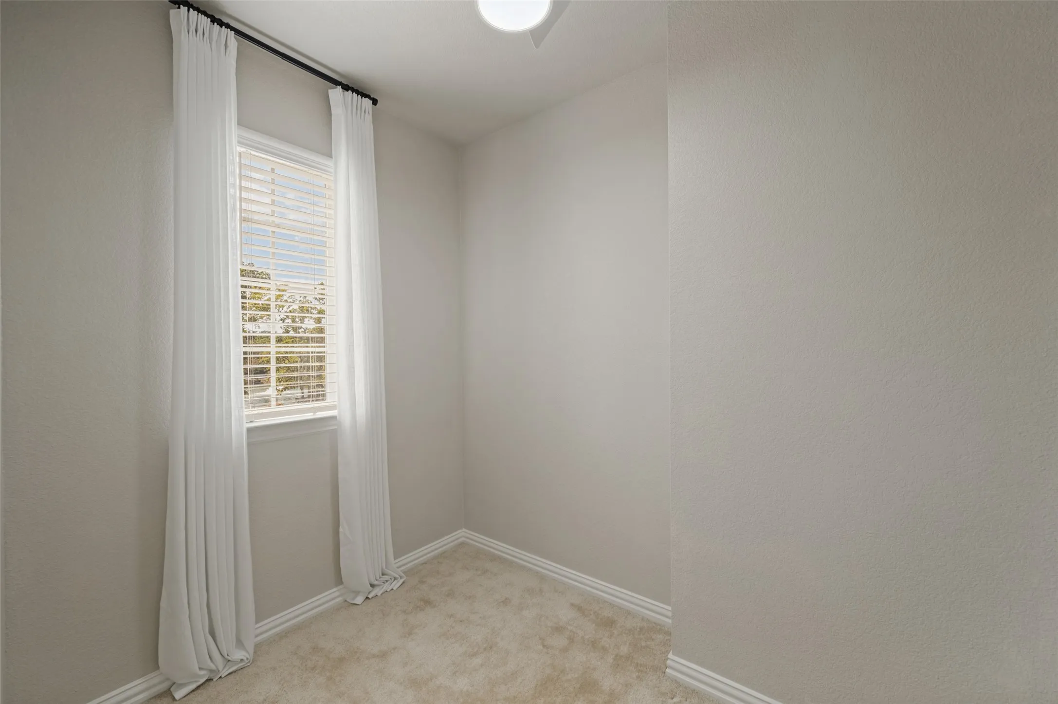 Window with blinds, wall-to-wall carpeting, and baseboard trim