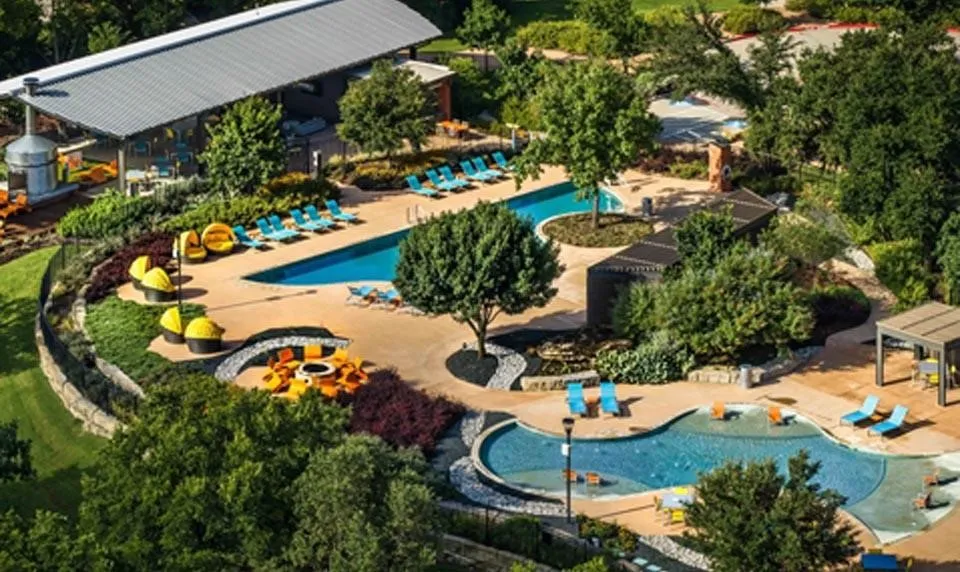 Resort-style pool area featuring multiple swimming pools, a covered outdoor lounge, and structured landscaping