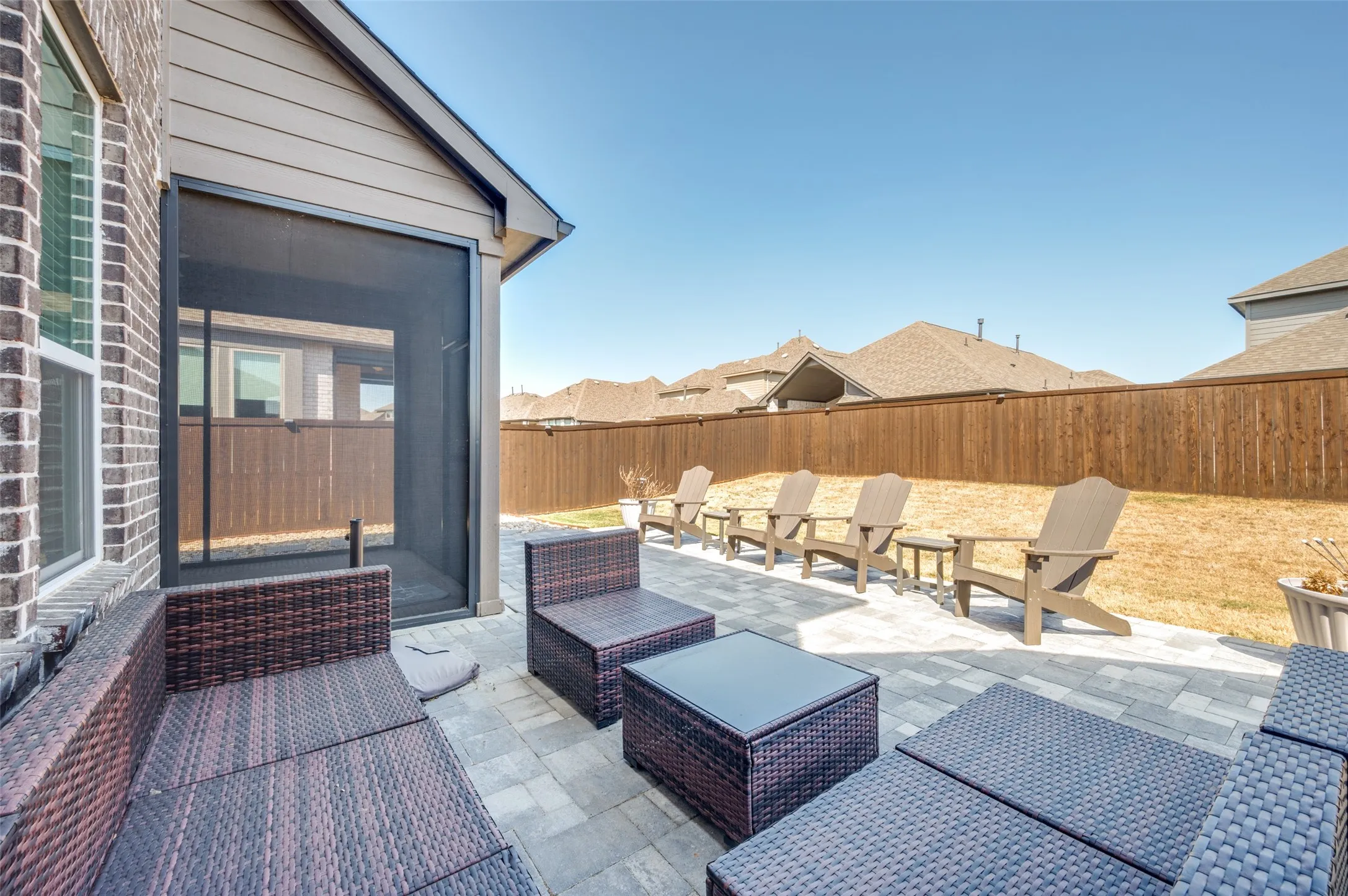 Screened patio with brick and siding exterior, paver flooring, and a wooden privacy fence