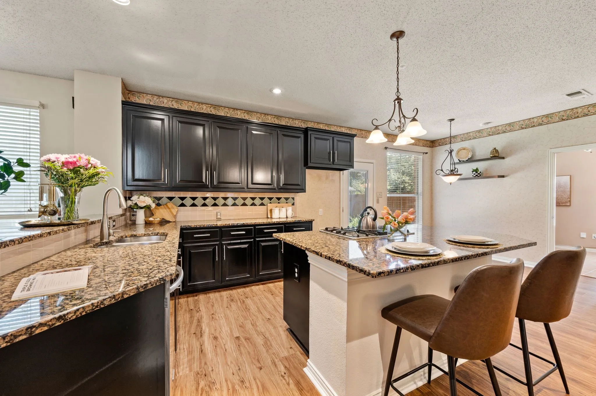 Kitchen featuring dark wood cabinetry, light-toned countertops, a built-in island with seating, a gas cooktop, and wood-finish flooring