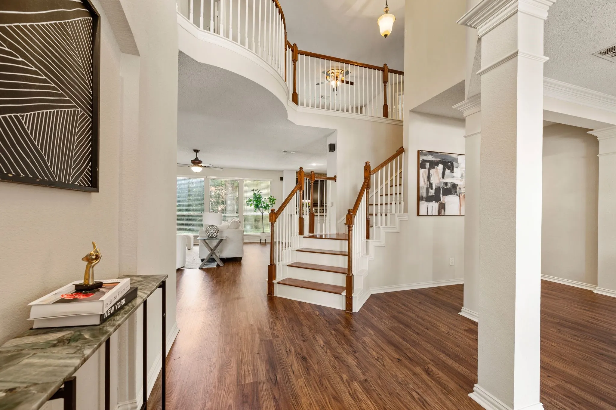 Two-story foyer with wood-finish flooring, a grand staircase with wood handrails, and a second-story balcony