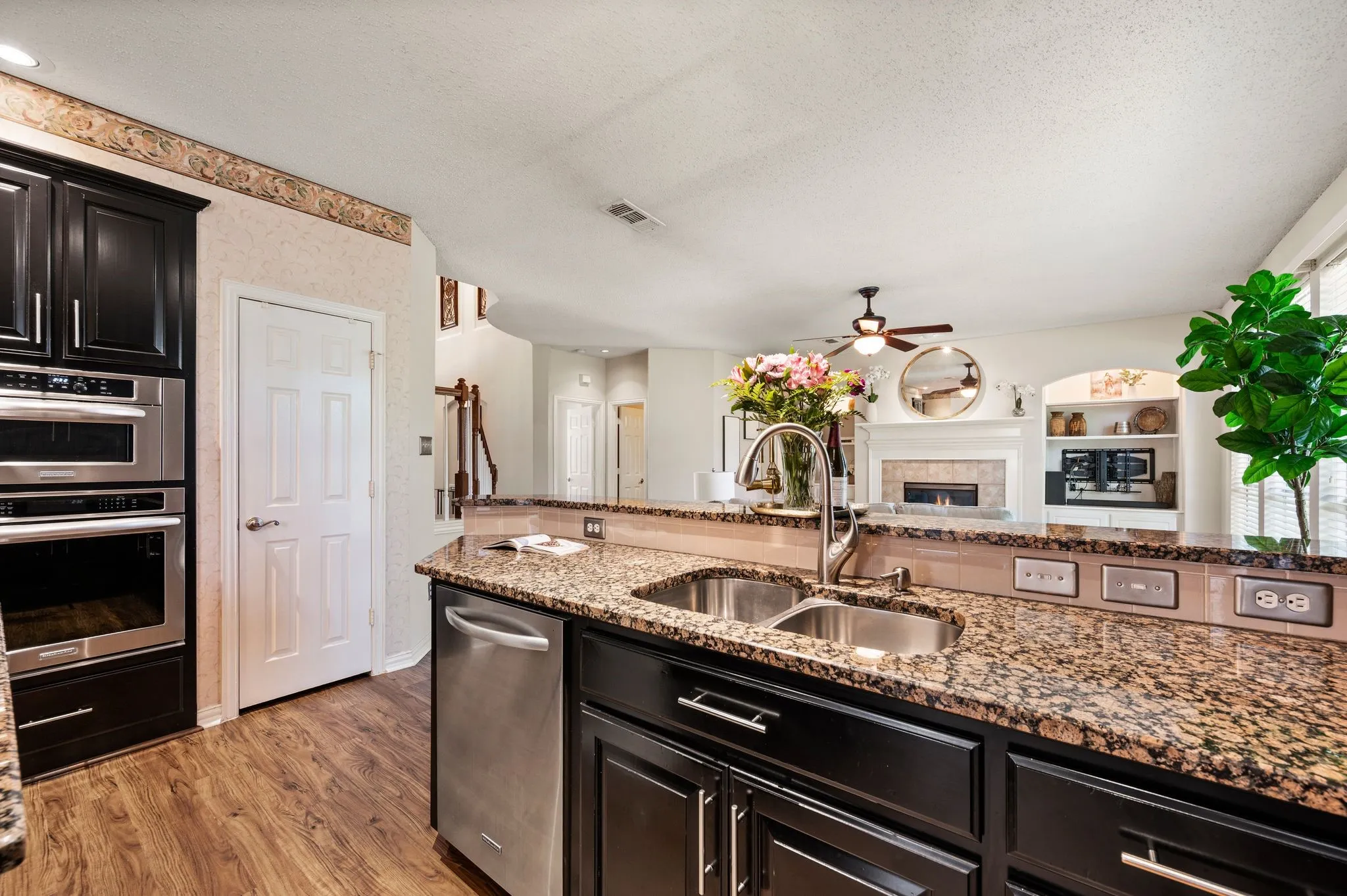 Kitchen featuring dark cabinetry, stainless steel appliances, a double basin sink, and granite countertops