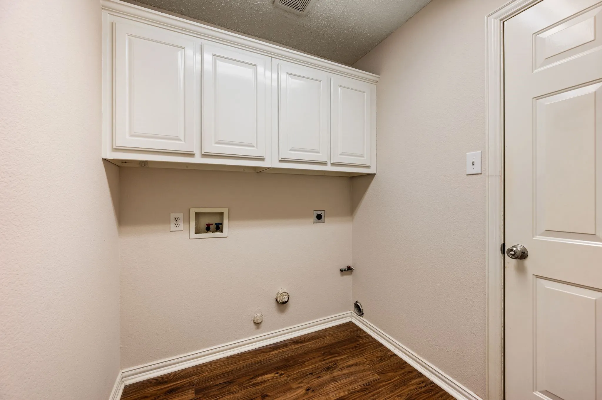 Wood-finish flooring, white cabinetry, and white baseboards