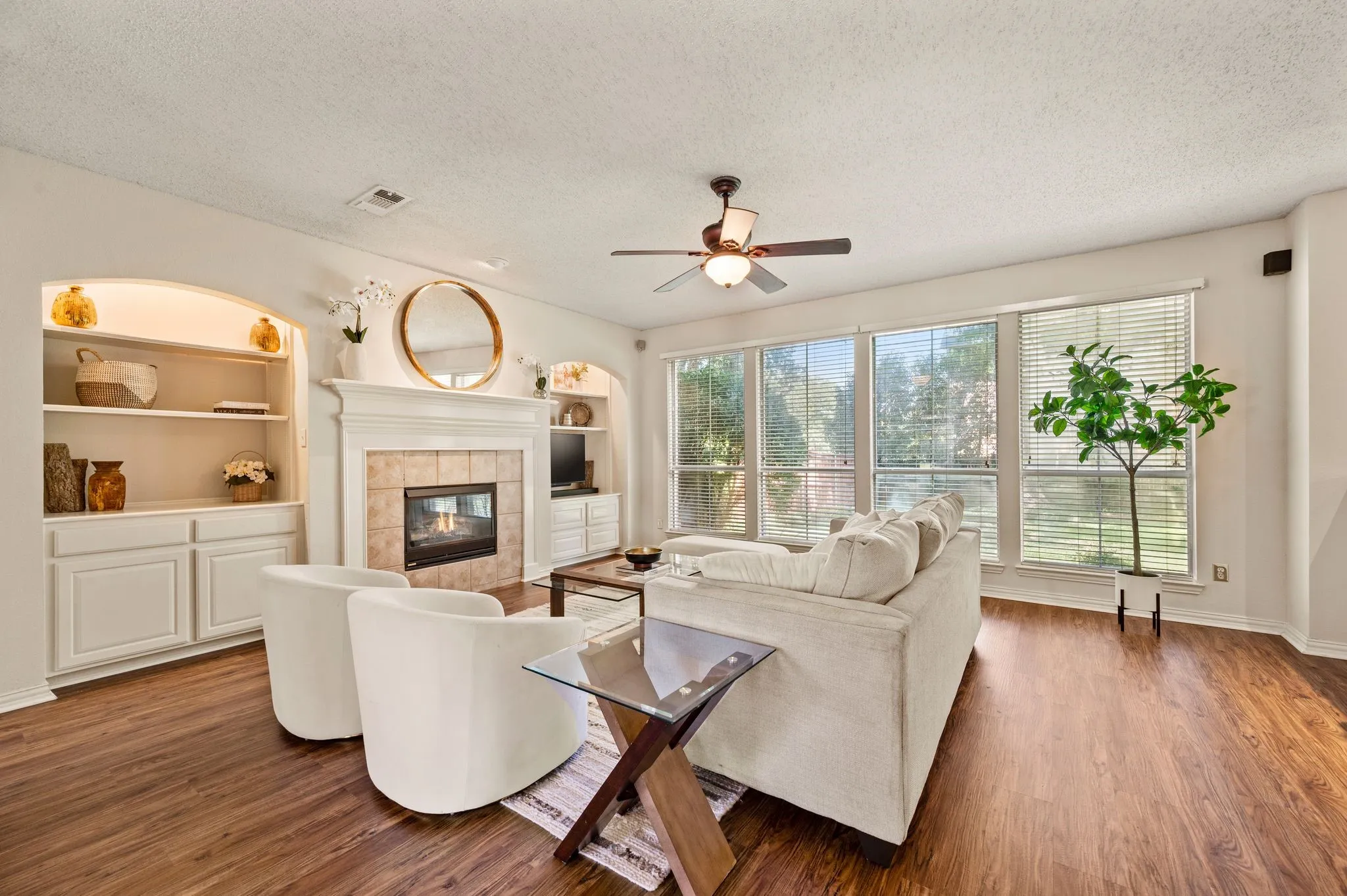 Wood-finish flooring, built-in shelving with arched recesses, and a tile-surround fireplace with a classic mantel
