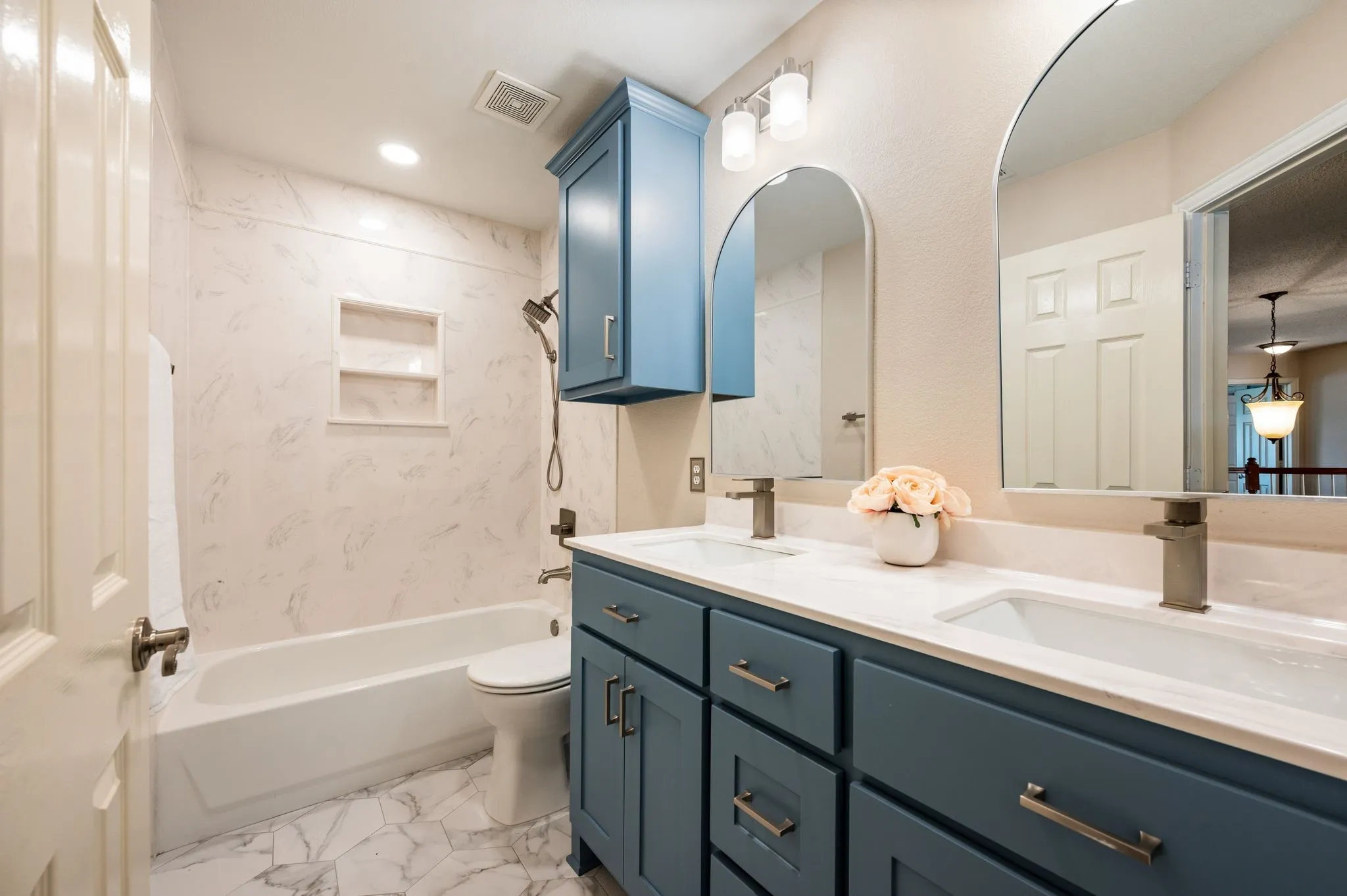 Dual vanity with undermount sinks, white countertop, and arched mirrors