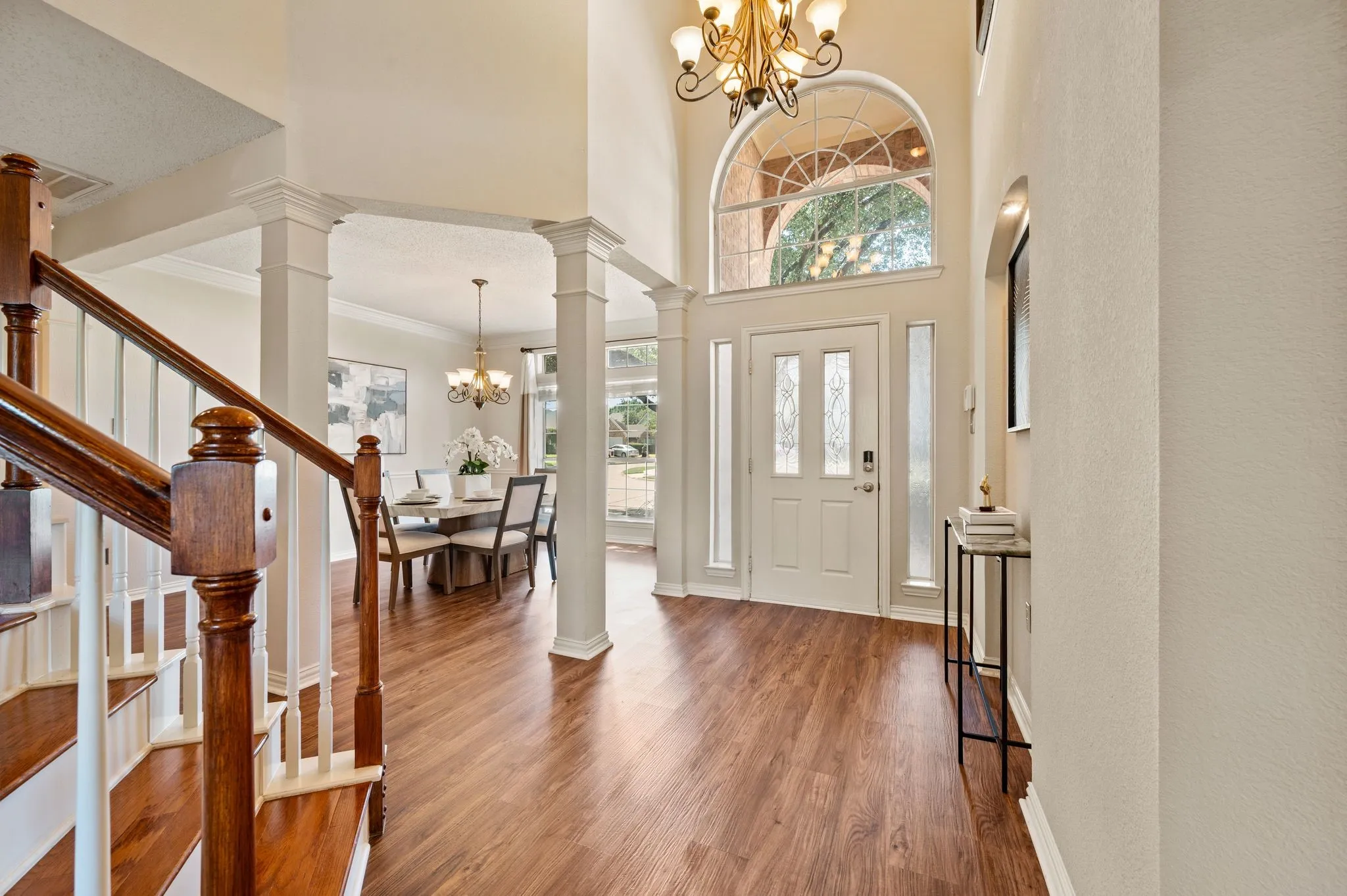 Two-story foyer with a decorative arched window, wood-finish flooring, and a chandelier