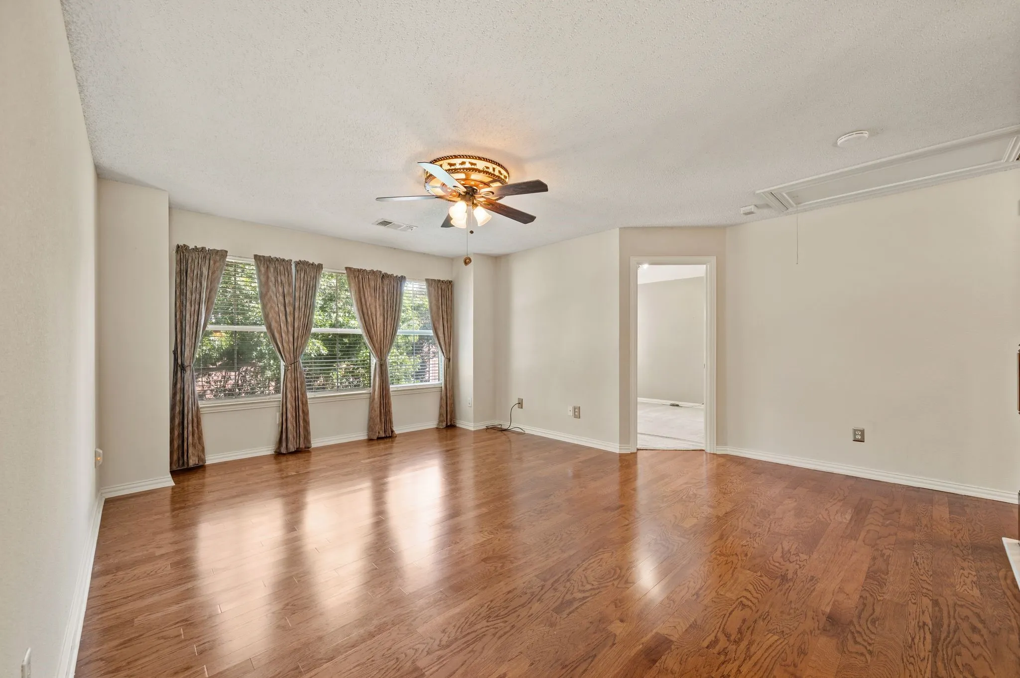 Hardwood flooring, multiple windows, ceiling fan, and painted walls