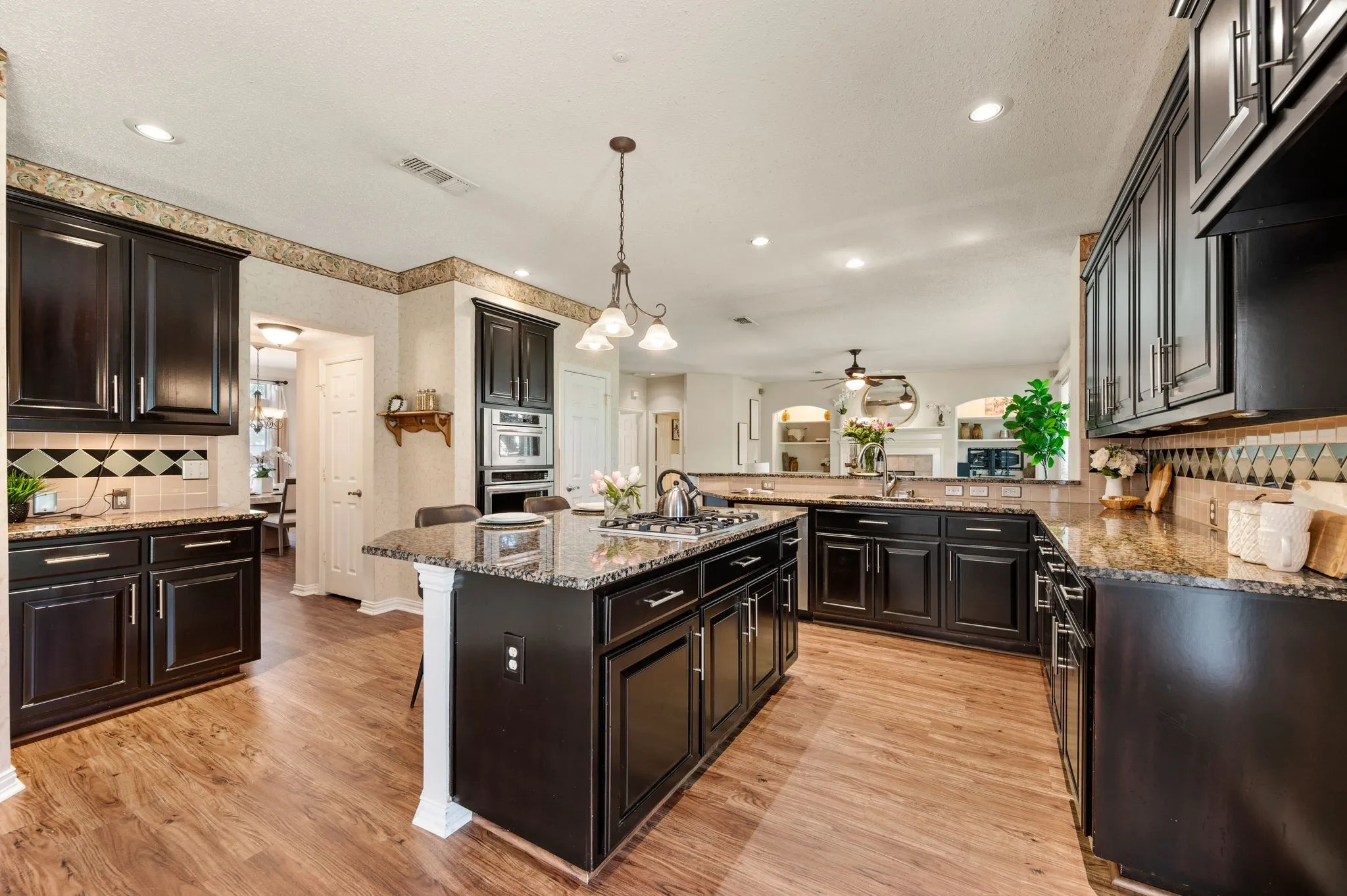 Kitchen featuring wood-finish flooring, dark cabinetry, granite countertops, and recessed lighting