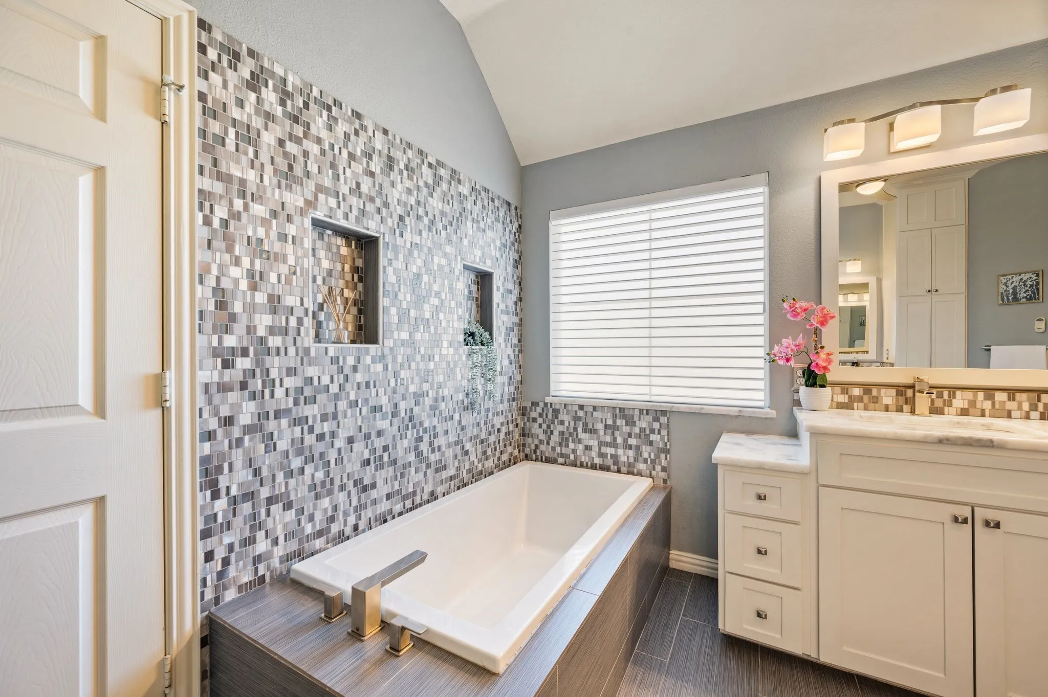 Soaking tub with a mosaic tile surround and built-in niches
