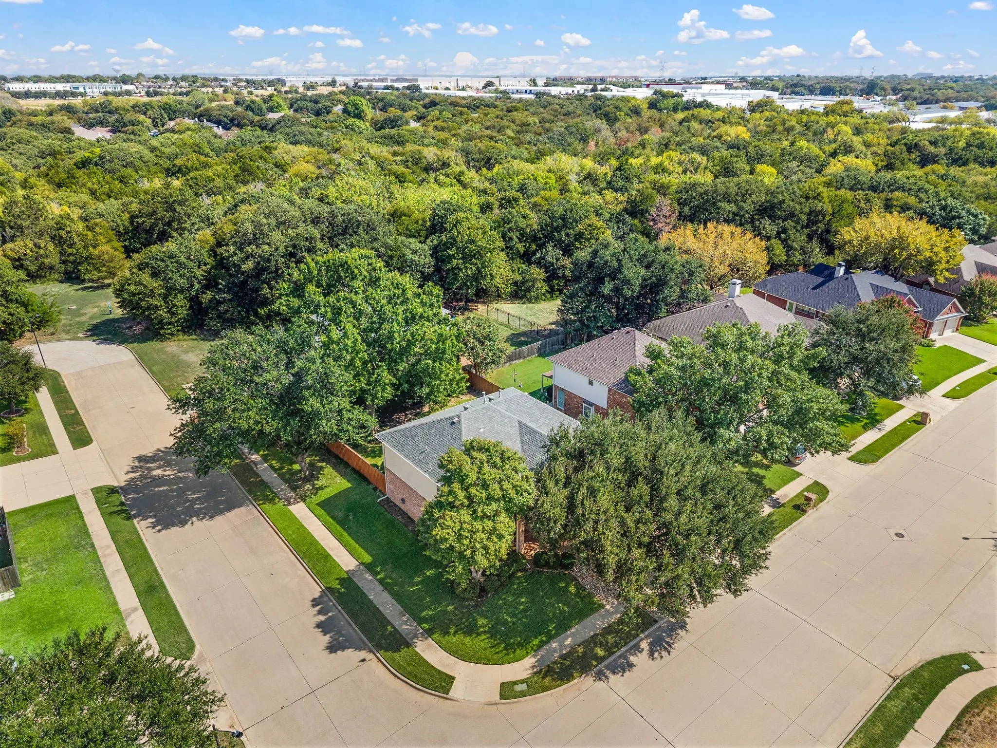 Aerial perspective showcasing residential properties with mature trees, paved streets, and a large expanse of natural greenery