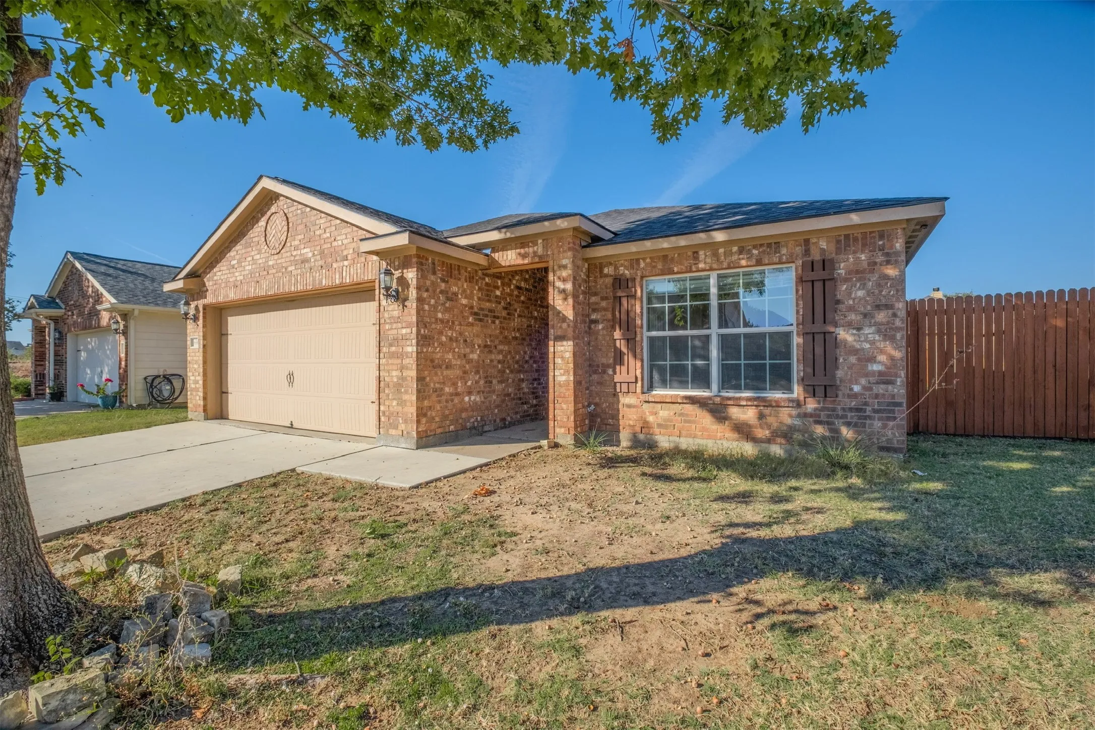 Single story home with driveway, brick siding, and a garage