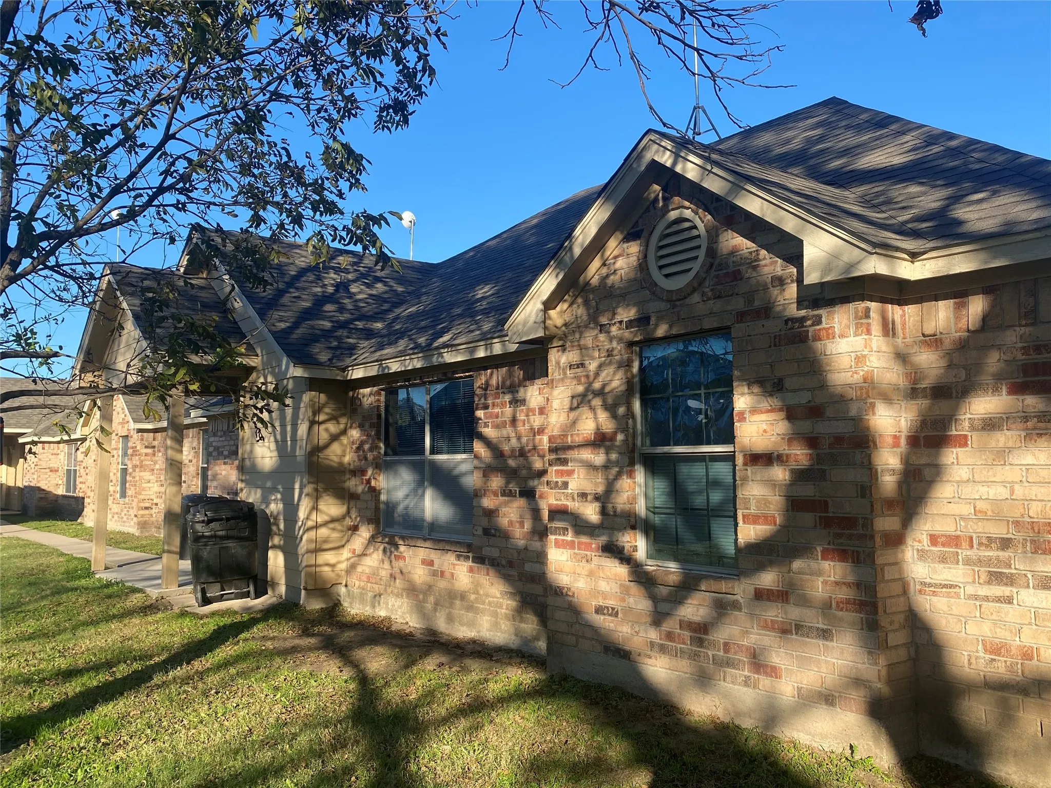 Brick exterior with multiple gabled rooflines, a prominent front window, and a circular vent feature