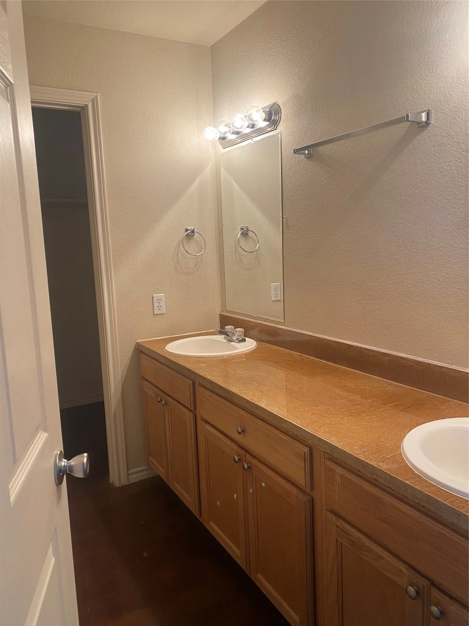 Dual vanity with wood-finish cabinetry, integrated sinks, and a full-width mirror