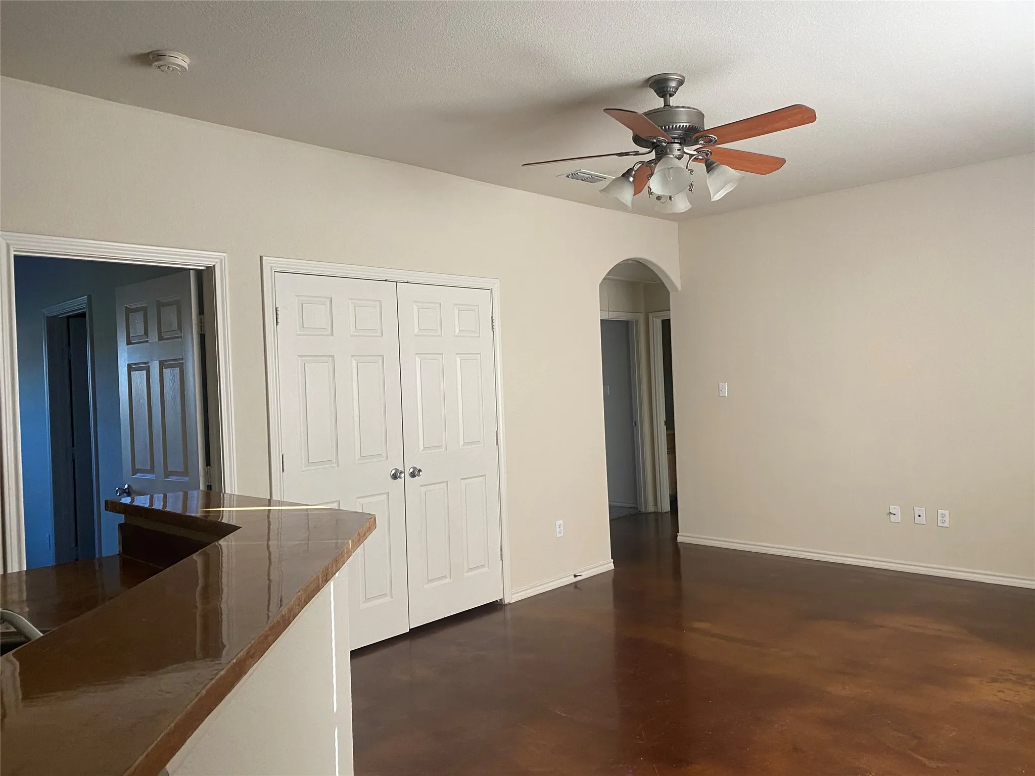 Dark-toned flooring, white walls, and a ceiling fan with integrated lighting