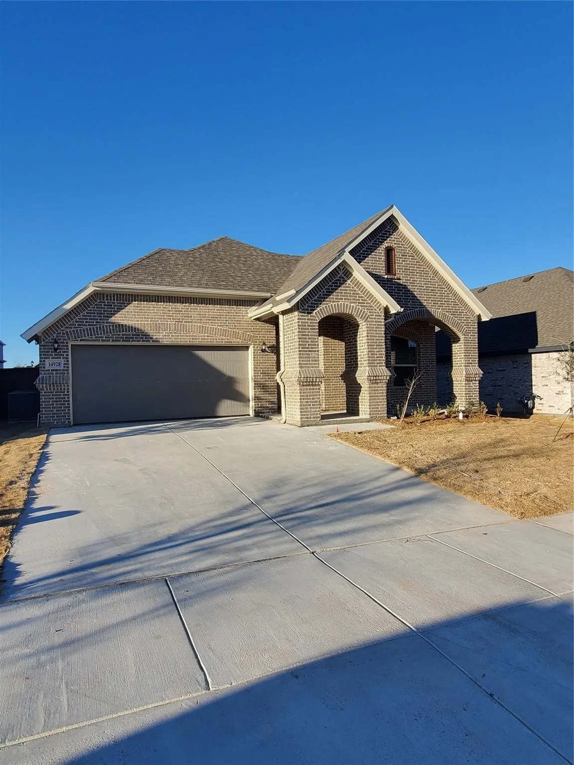 Brick exterior with a gabled entry, attached garage, and a concrete driveway