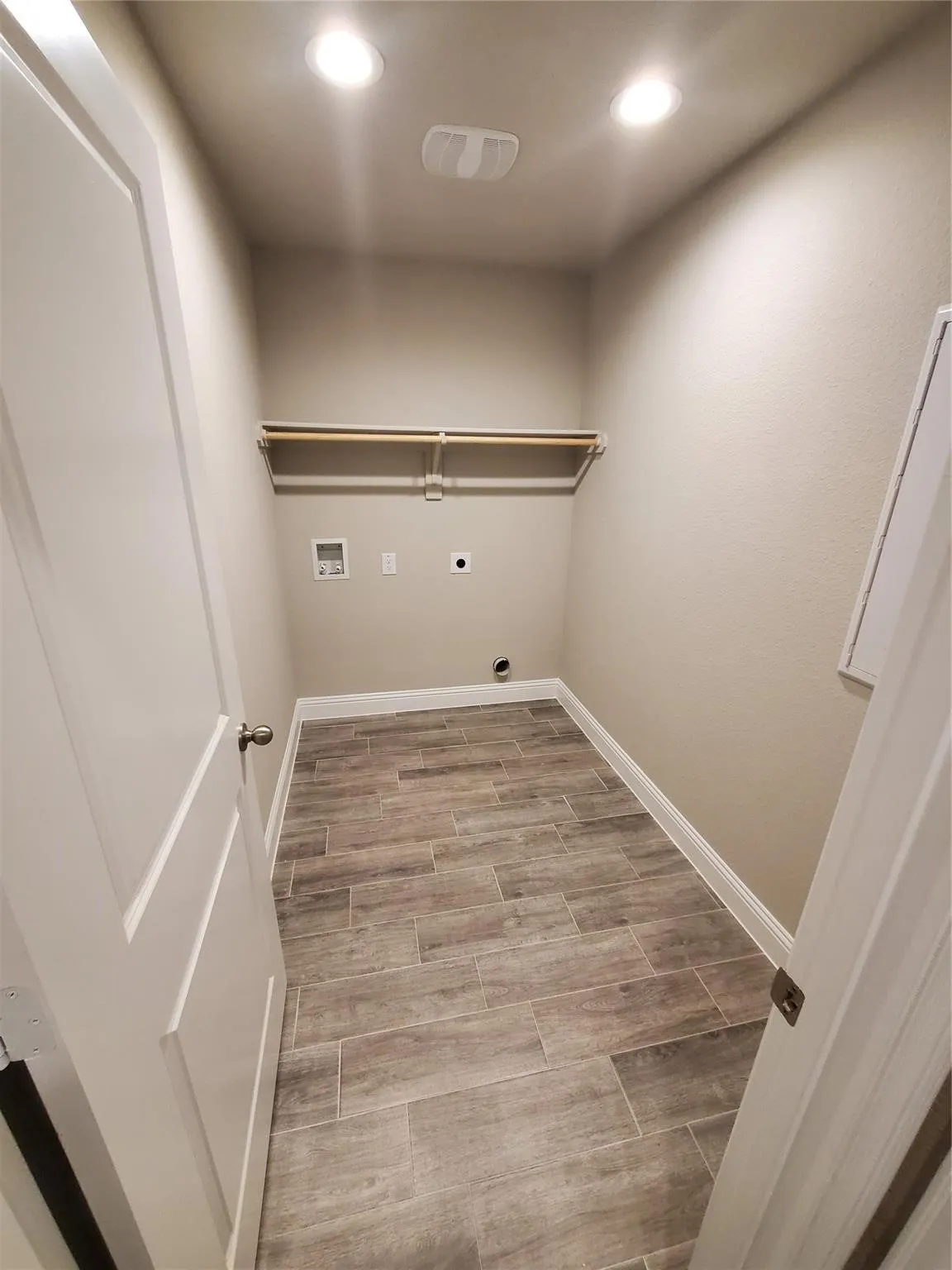 Wood-look plank tile flooring, built-in shelving, two overhead recessed lights, and a ceiling-mounted light fixture